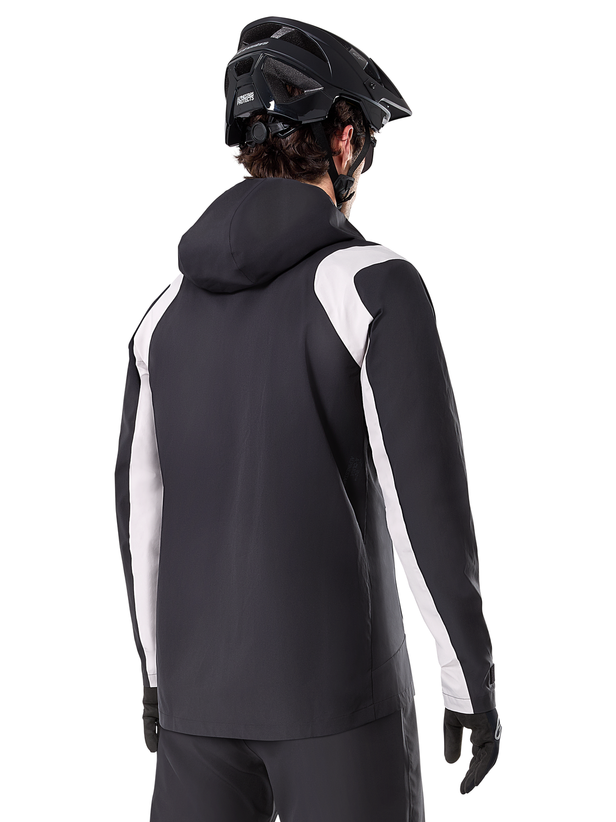 Alpinestars A-Dura Rain Jacket, casaco de chuva de Mountain Bike, preto com painéis brancos nas mangas, vista traseira de ciclista a usar capacete de BTT preto e luvas, construção técnica impermeável de 2,5 camadas, vestuário de mountain bike