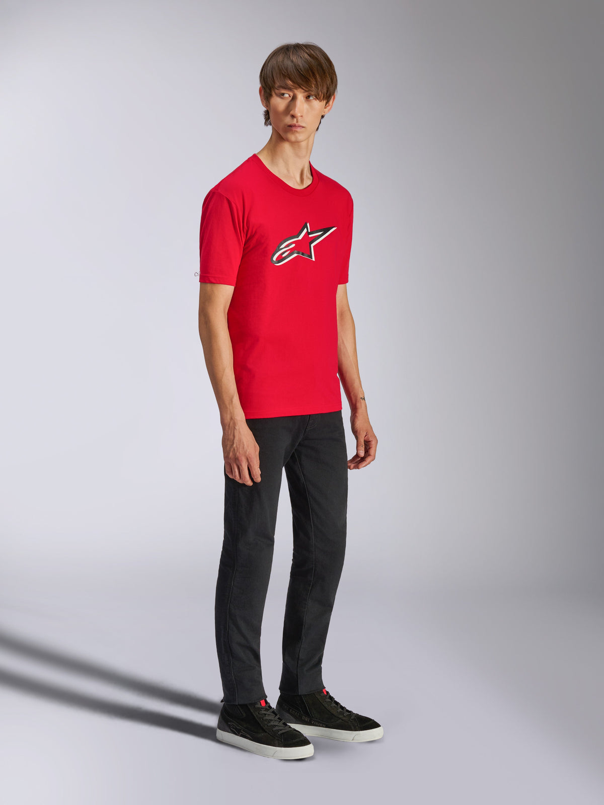 Alpinestars Ageless Shadow CSF Tee, t-shirt de manga curta vermelha, com um logótipo Ageless grande no peito, vestida por um modelo com calças pretas e ténis, streetwear casual de desportos motorizados