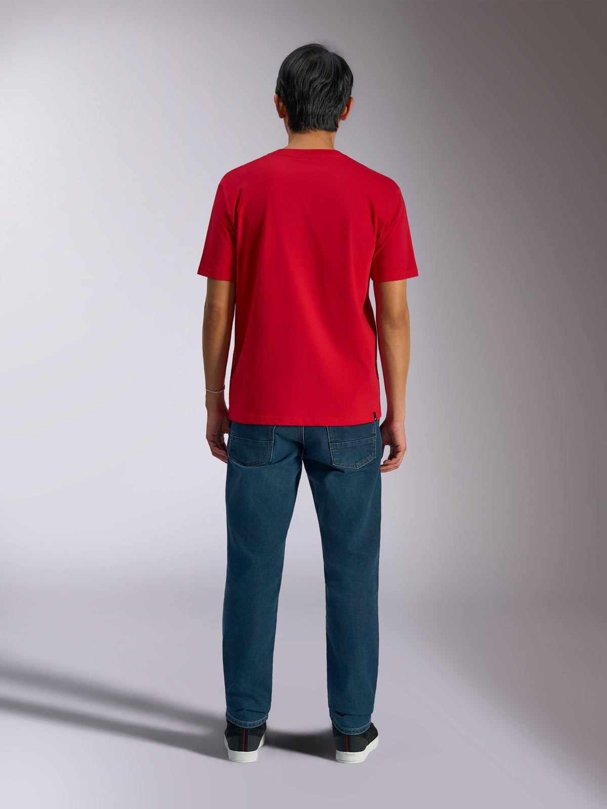 Alpinestars Ageless Shadow CSF Tee, vista traseira de t-shirt vermelha de manga curta, usada com calças de ganga azul escuro e sapatilhas pretas, streetwear casual de desportos motorizados