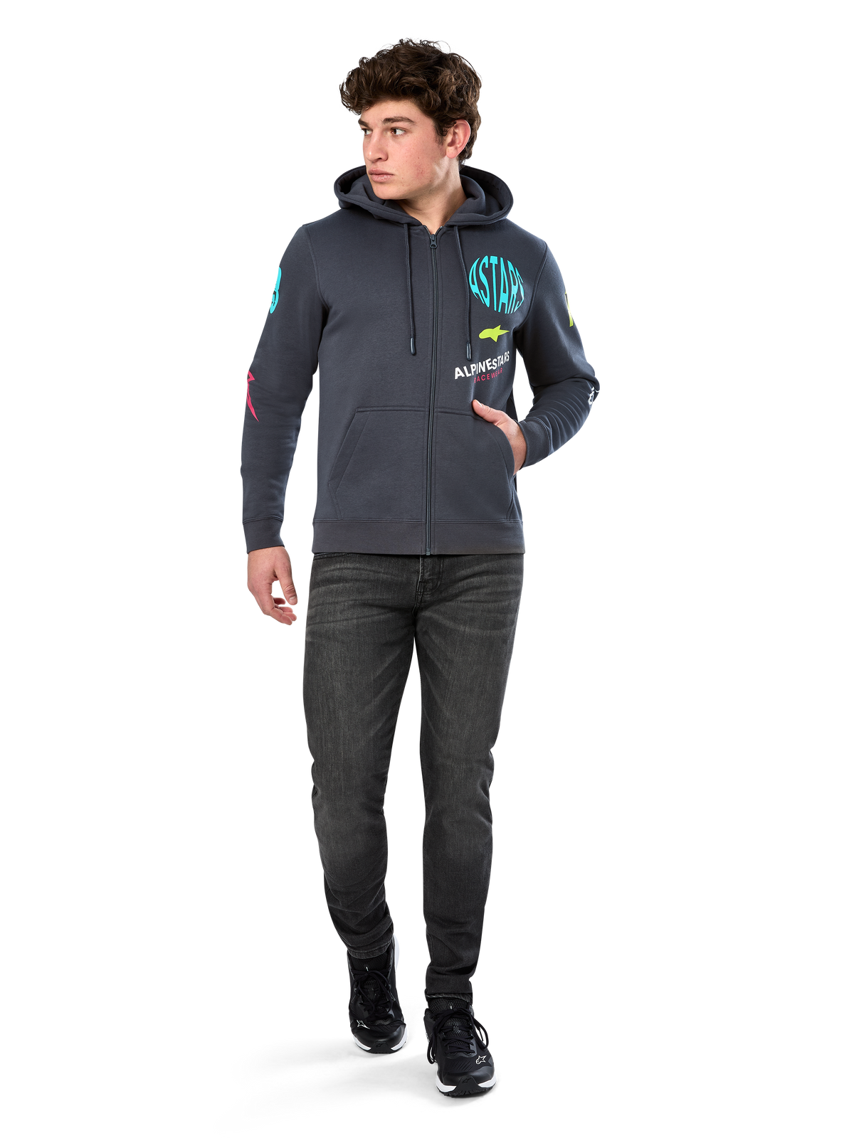 Alpinestars Variegate Hoodie, hoodie de lã com fecho frontal, cinza Gunmetal, usado por um modelo com calças de ganga pretas e sapatilhas, com a marca 'ASTARS' em verde-água e logótipos coloridos nas mangas e no peito, streetwear casual inspirado no desporto motorizado