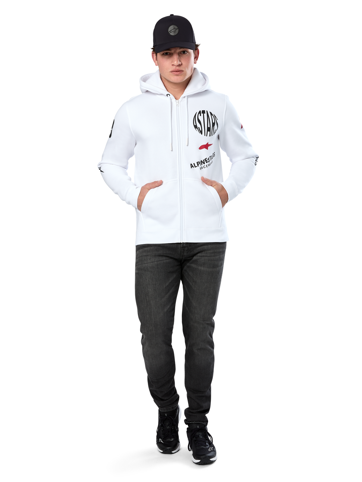 Hoodie Variegate Alpinestars, hoodie branco de lã com fecho de correr, arte com múltiplos logótipos com 'ASTARS' e logótipo de estrela vermelha no peito, detalhes gráficos nas mangas, usado por modelo com boné preto e calças de ganga pretas, streetwear casual de desportos motorizados