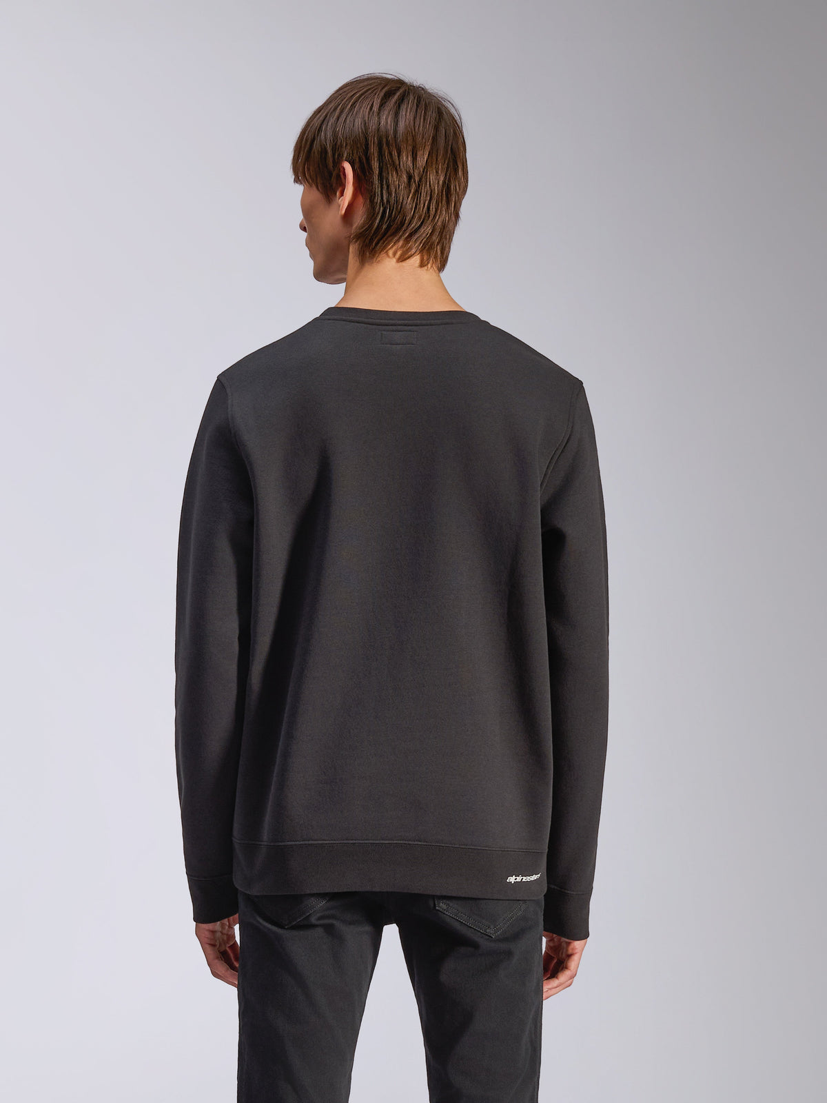 Alpinestars Positive Crew, sweatshirt sem capuz, preta, vista traseira, com punhos e bainha canelados e um pequeno logótipo branco na anca, design casual inspirado no desporto motorizado