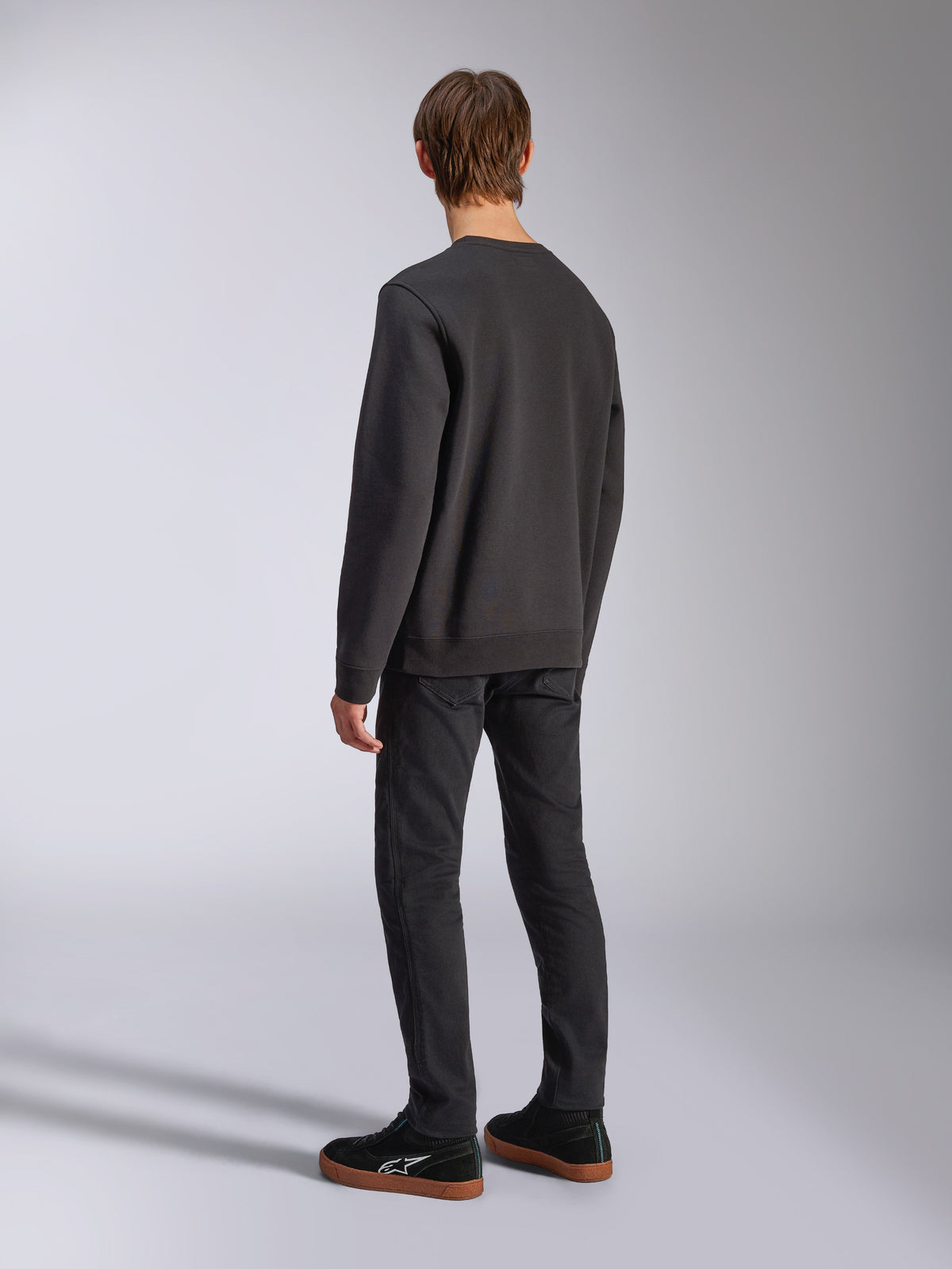 Alpinestars Positive Crew, sweatshirt preta, vista traseira no modelo, streetwear casual de inspiração motorsport, com bainha e punhos canelados.