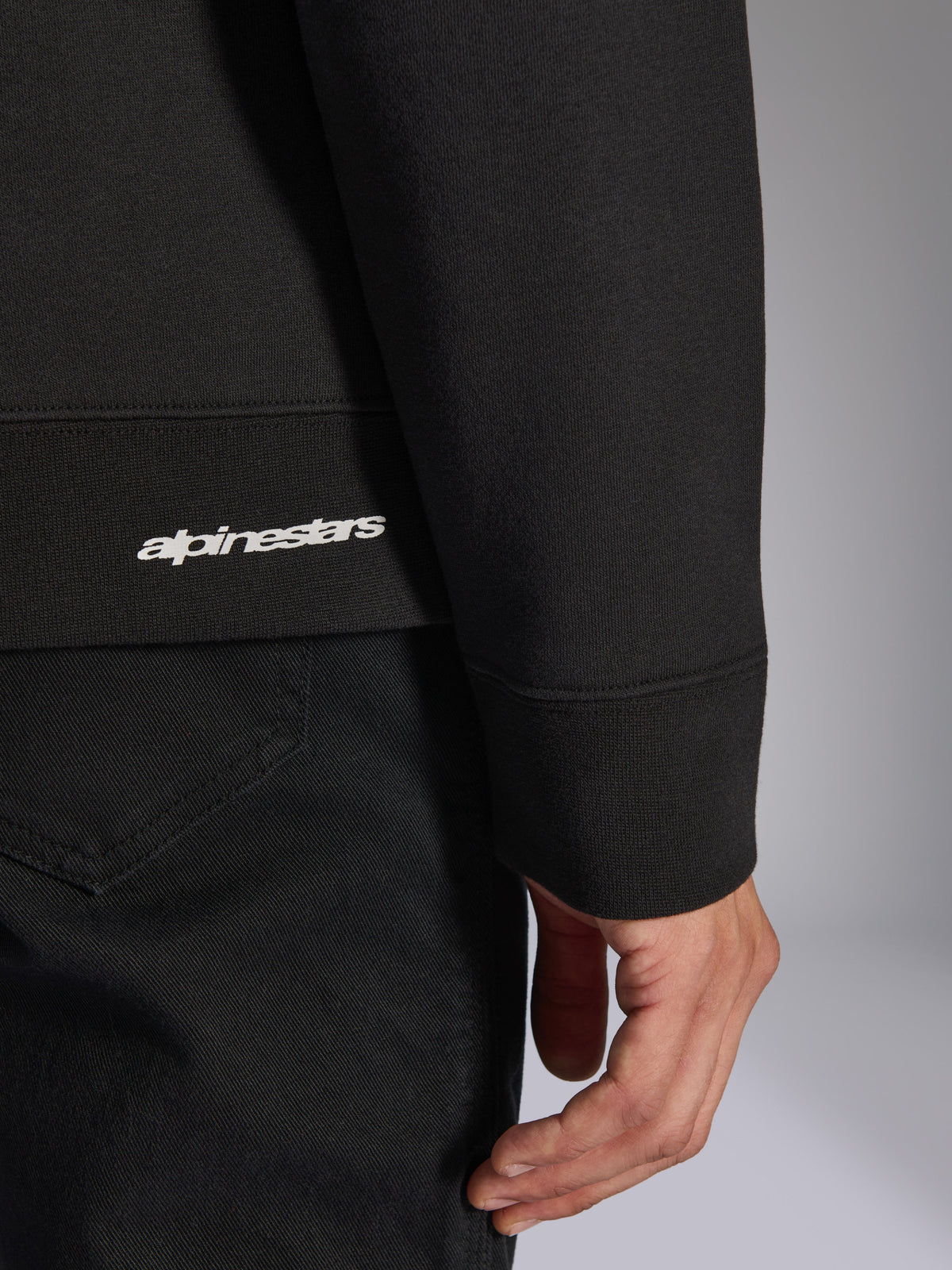 Alpinestars Positive Crew, sweatshirt preta, pormenor da bainha e punho canelados com logótipo Alpinestars branco, textura de tecido premium, roupa desportiva casual inspirada no desporto motorizado