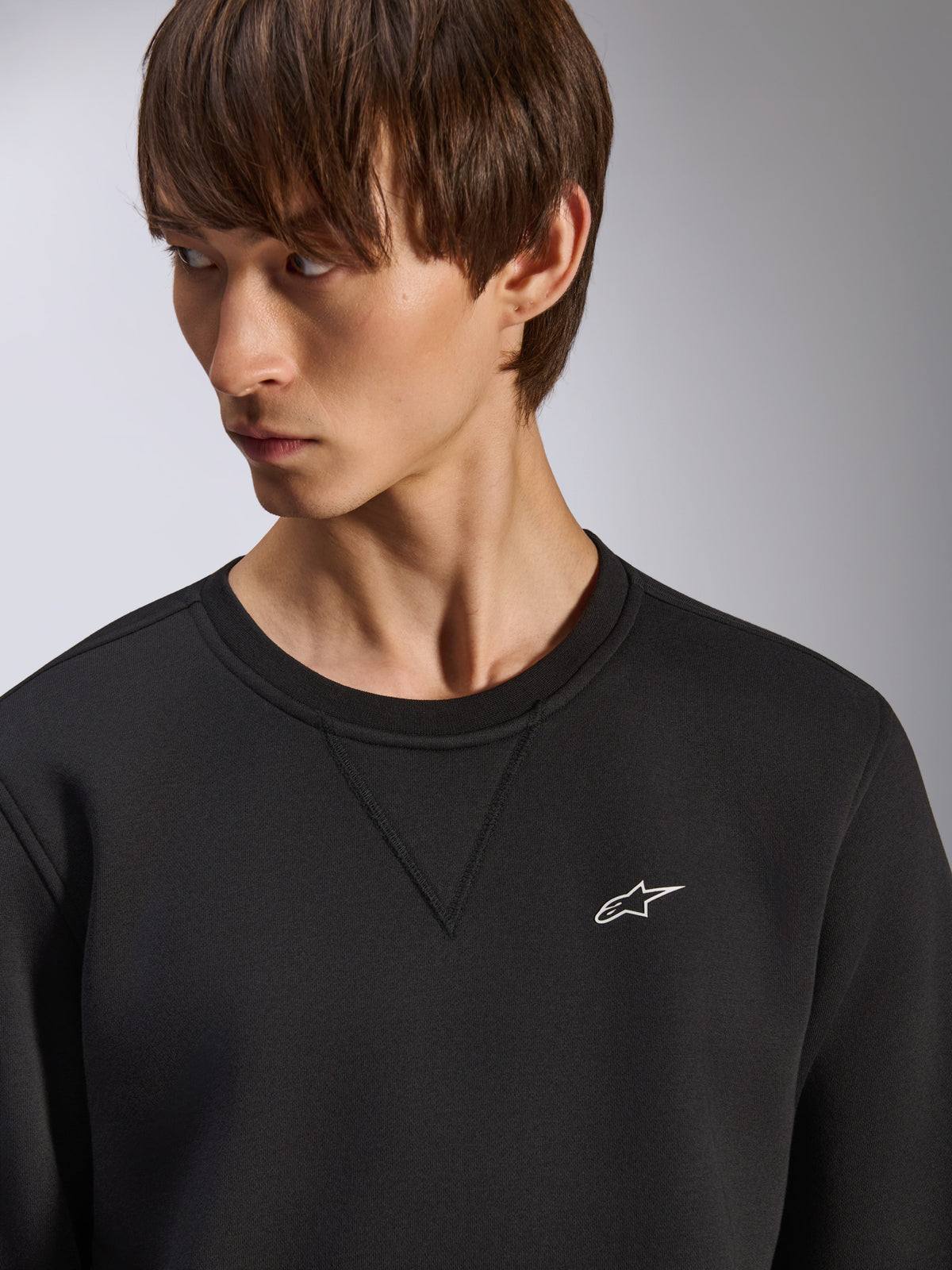 Sweatshirt Alpinestars Positive Crew, gola redonda preta com detalhe de costura em V na gola, pequeno logótipo branco da Alpinestars no lado esquerdo do peito, streetwear casual inspirado no desporto motorizado