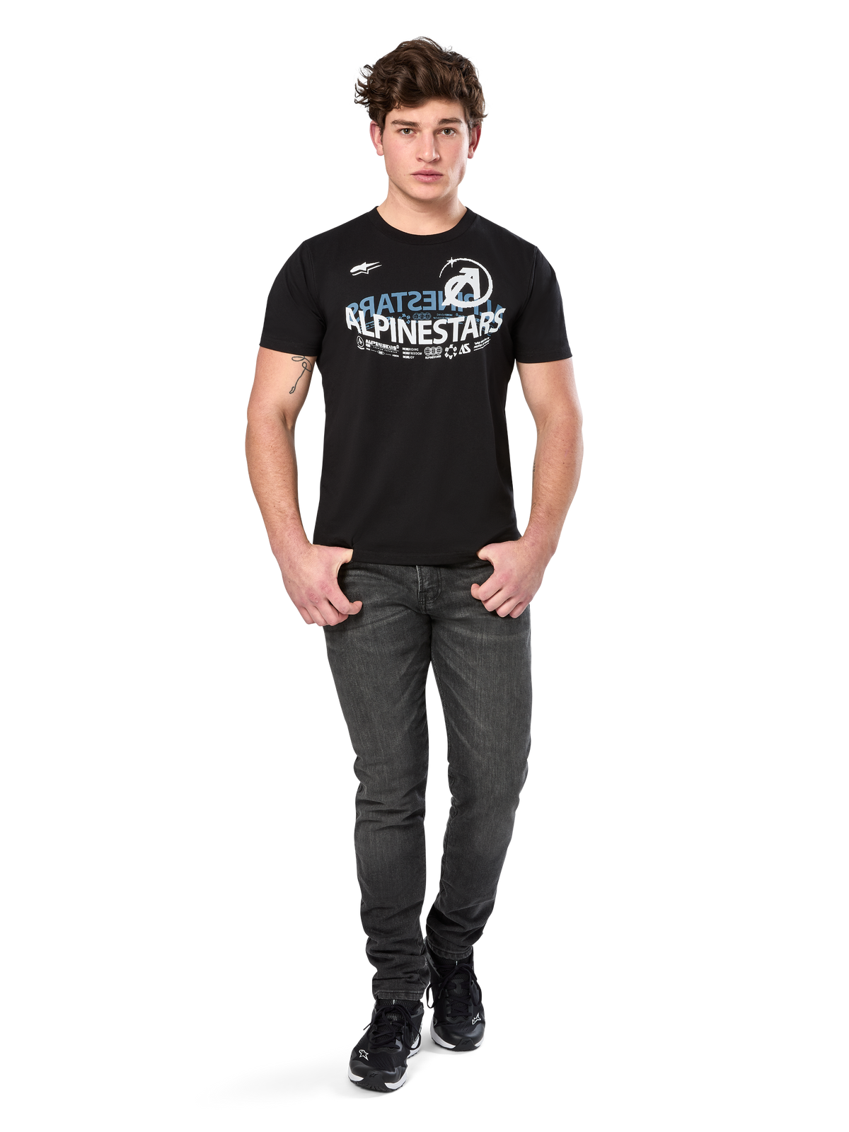 T-shirt Alpinestars Semicircle CSF, t-shirt de manga curta, preta com gráfico curvo em branco e azul claro no peito, vestida por modelo com calças de ganga cinzento escuro e sapatilhas pretas, streetwear casual de desportos motorizados