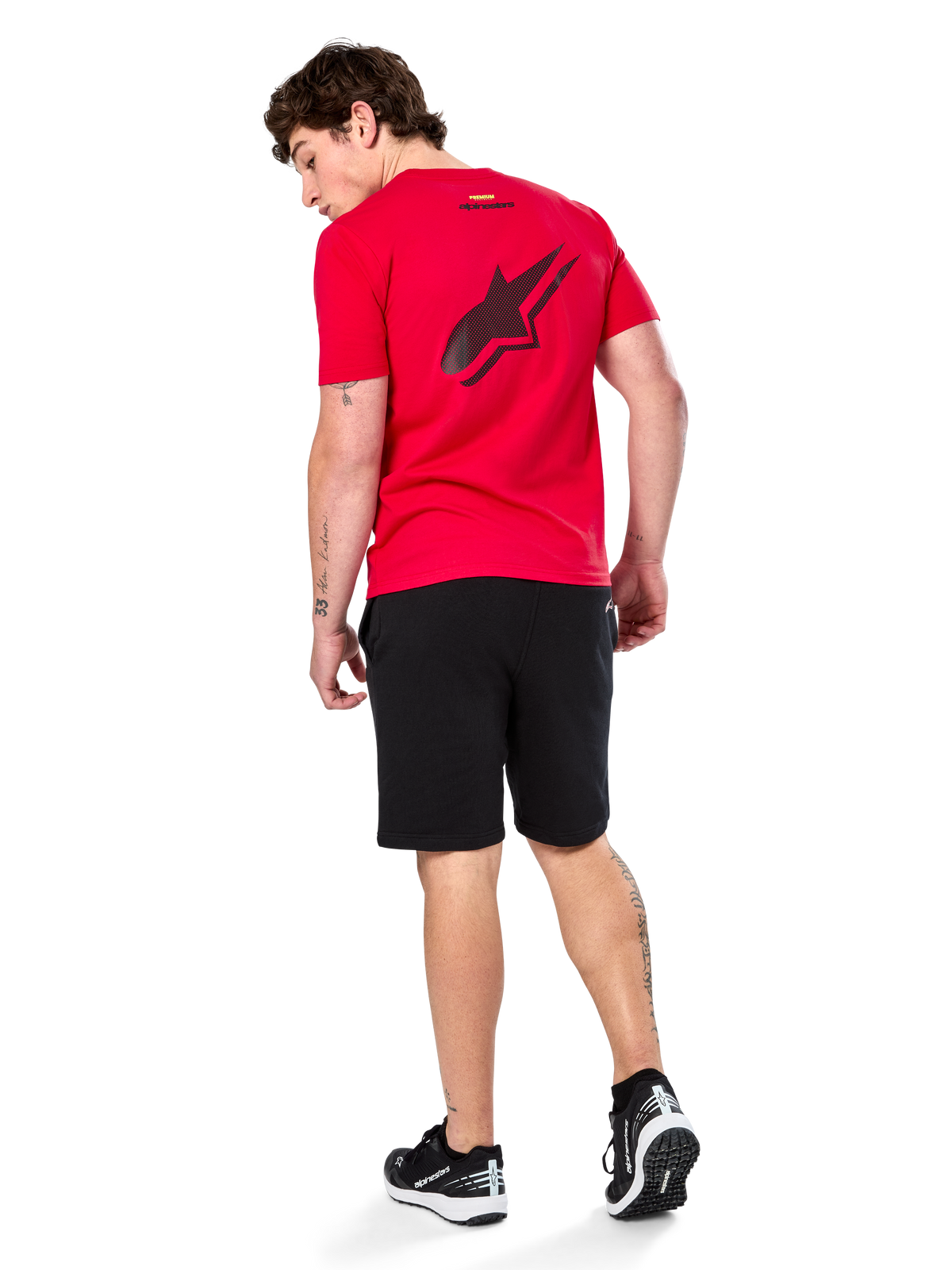 T-shirt Alpinestars Formulate Csf, t-shirt de manga curta, vermelha, logótipo Astars preto perfurado de grandes dimensões nas costas, usada com calções pretos e ténis, streetwear casual inspirado no desporto motorizado