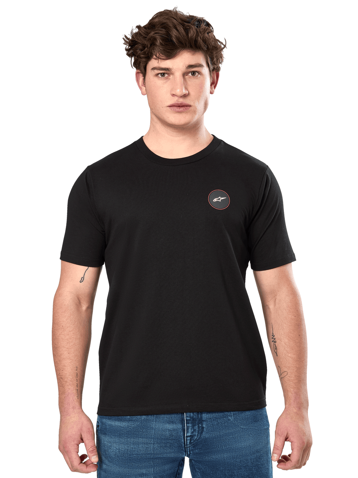 Alpinestars Dot Carbon CSF Tee, t-shirt de manga curta, preta, pequeno logótipo circular no peito com Astar branca e rebordo vermelho, vestida por um modelo com calças de ganga azuis, streetwear casual de motorsport