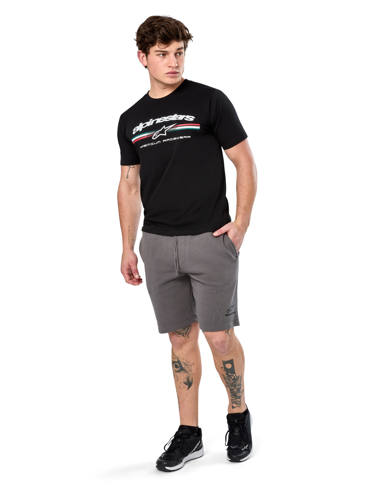 Alpinestars Prevail Csf Tee, t-shirt de manga curta, preta, logótipo Alpinestars branco com risca tricolor estilo paddock, usada com calções cinzentos e ténis pretos, streetwear casual de motorsport