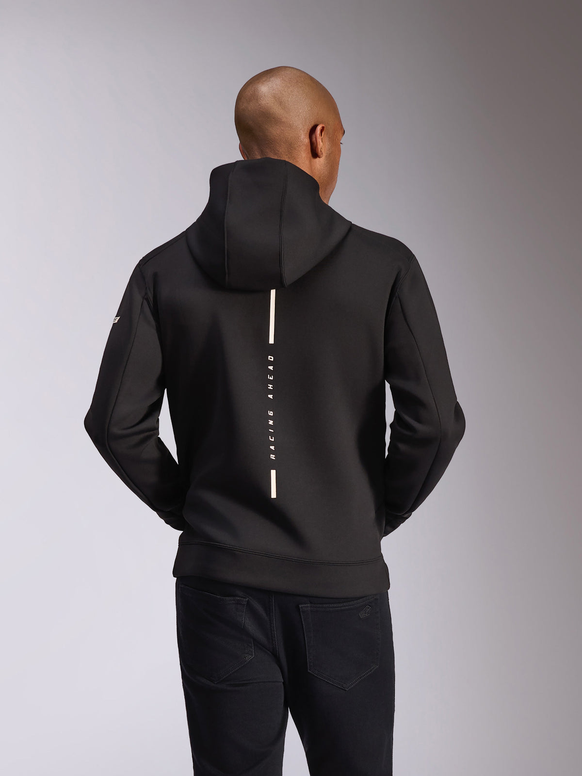 Alpinestars Insight Hoodie, vista traseira, preto, risca branca vertical com o texto 'RACING AHEAD', logótipo da marca na manga, streetwear casual inspirado no desporto motorizado