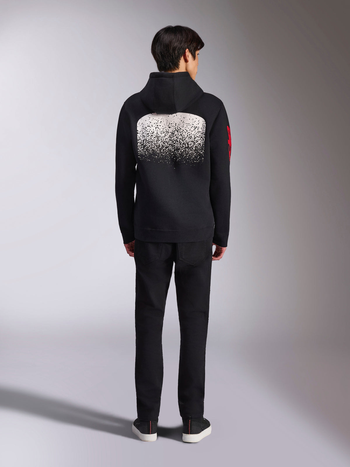 Camisola com Capuz Alpinestars Obsessed, roupa desportiva casual, preta com grafismo de gradação MX branco nas costas, logótipo vermelho na manga, vista de costas, usada com calças pretas