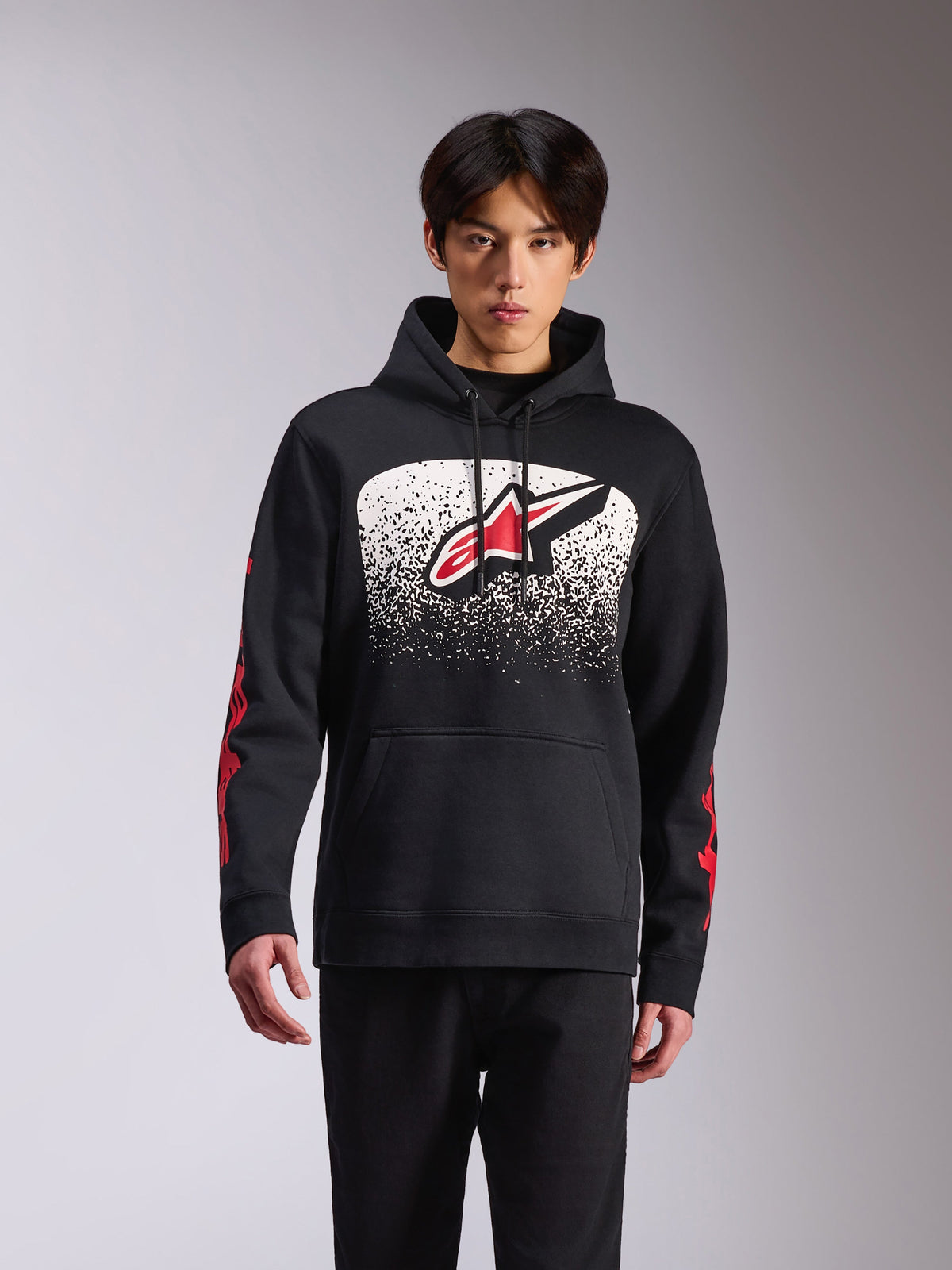 Alpinestars Obsessed Hoodie, roupa desportiva casual, camisola com capuz preta com um grande logótipo Astars frontal com gradação MX pontilhada a preto e branco, marca vermelha nas mangas, capuz com cordão e punhos canelados.
