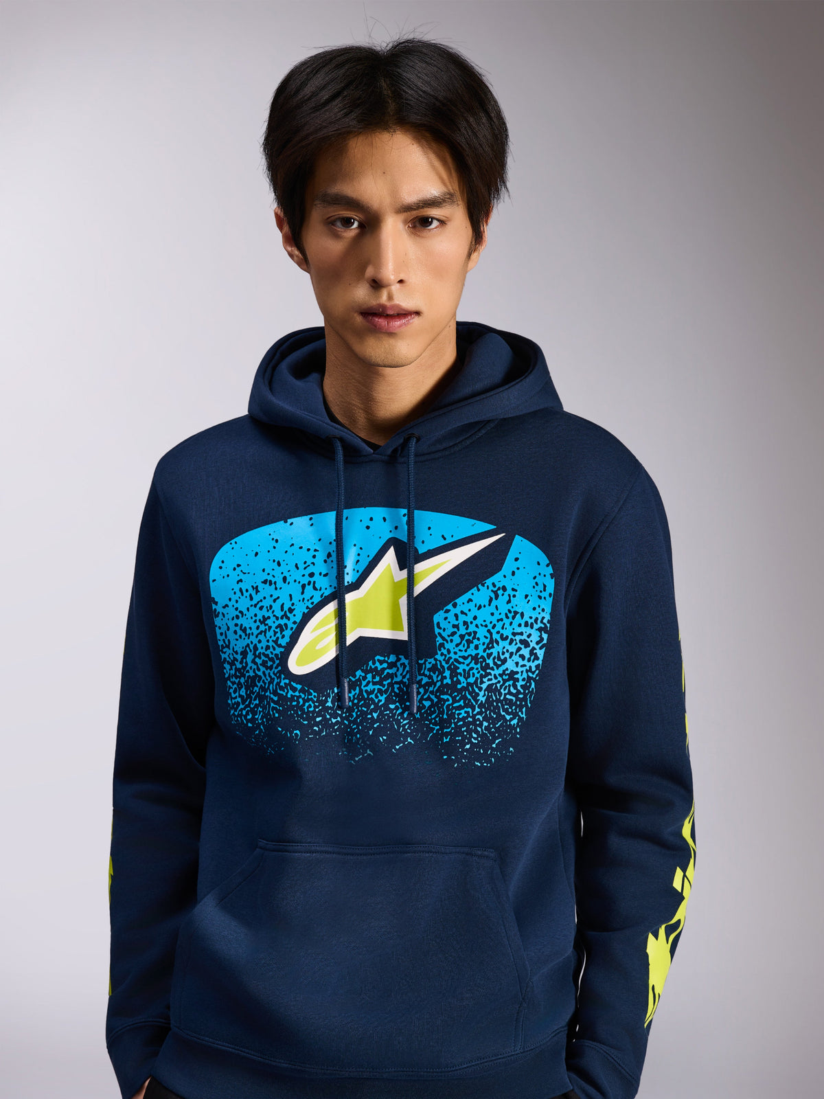 Alpinestars Obsessed Hoodie, camisola com capuz em fleece azul-marinho, logótipo Astars frontal com gradação MX azul e detalhes em verde-lima, logótipos amarelos nas mangas, streetwear casual inspirado no desporto motorizado