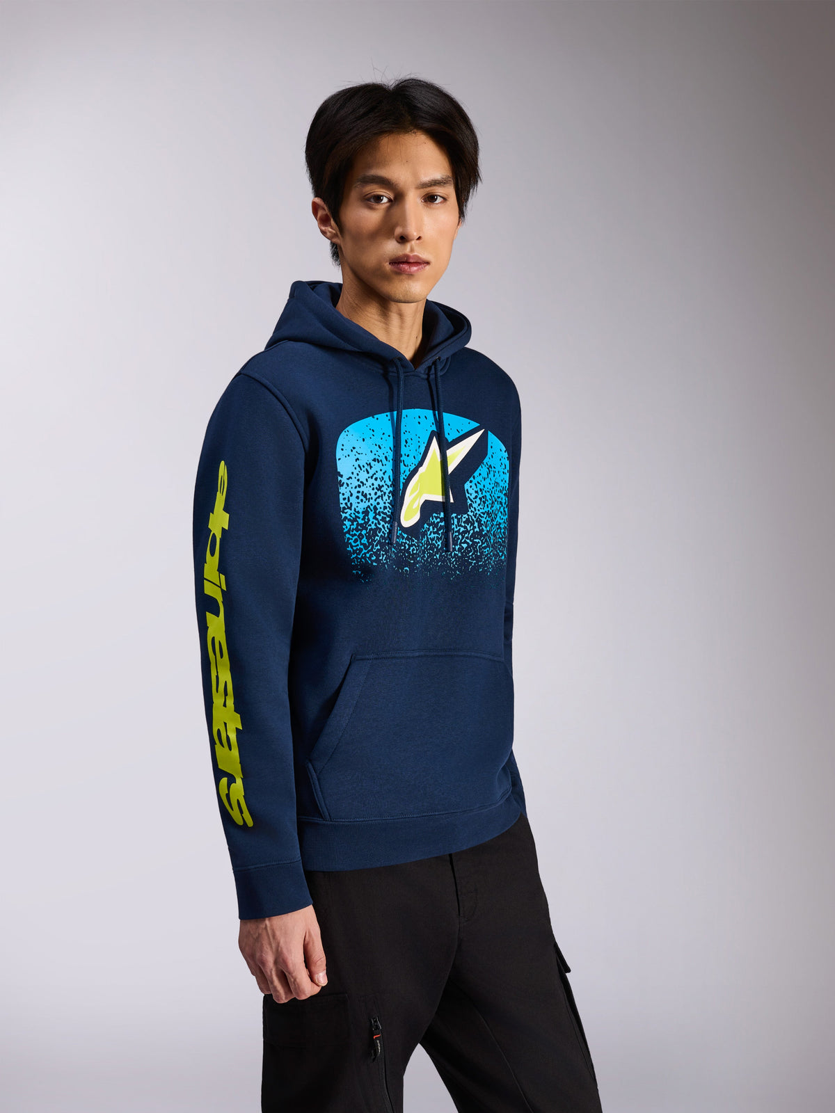 Alpinestars Obsessed Hoodie, azul marinho, camisola com capuz em fleece, apresentando o logótipo Astars frontal com gradação MX em azul claro e logótipo nominativo amarelo na manga, capuz com cordões, estilo streetwear casual de desportos motorizados