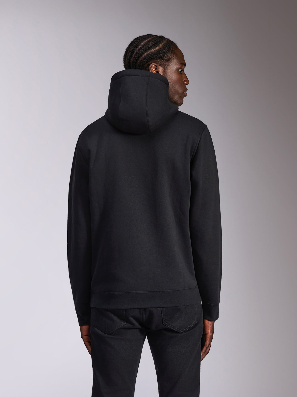 Alpinestars Pulse Hoodie, preto, vista traseira num modelo, estilo casual streetwear, camisola com capuz em fleece com design em preto sólido, punhos e bainha canelados, combinada com calças pretas