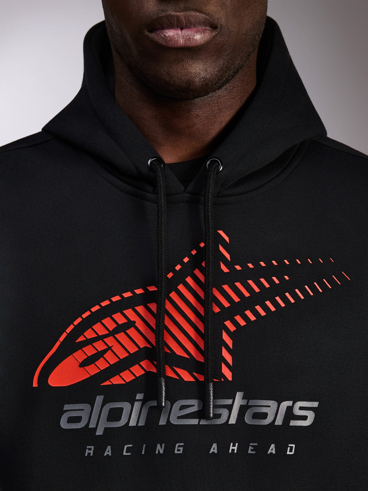 Alpinestars Pulse Hoodie, camisola preta com capuz, grande plano do peito com logótipo Astars vermelho com efeito speed line fade e branding prateado, cordões pretos com pontas mergulhadas, streetwear casual de desportos motorizados