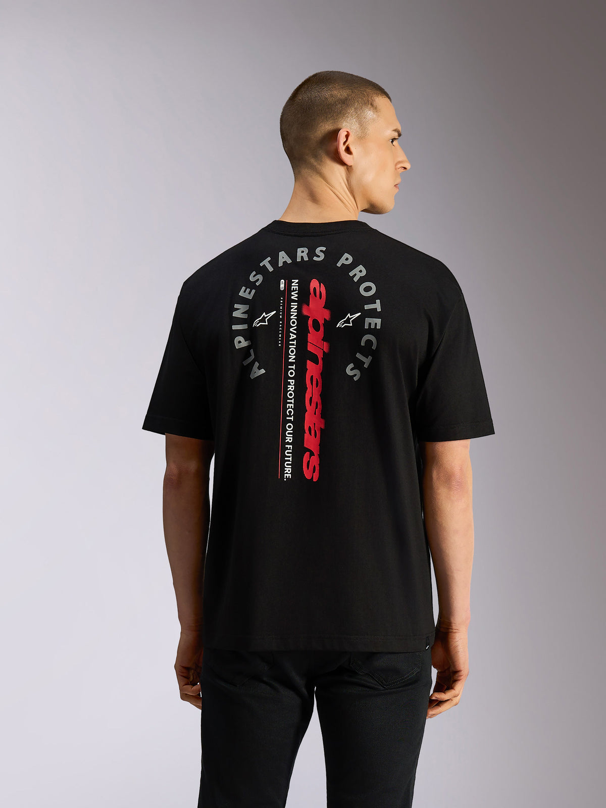 Alpinestars Overhang Oversized CSF Tee, Short Sleeve T-Shirt, Black, Back view showing vertical red Alpinestars wordmark and circular grey 'Alpinestars Protects' graphic, casual motorsport-inspired streetwear