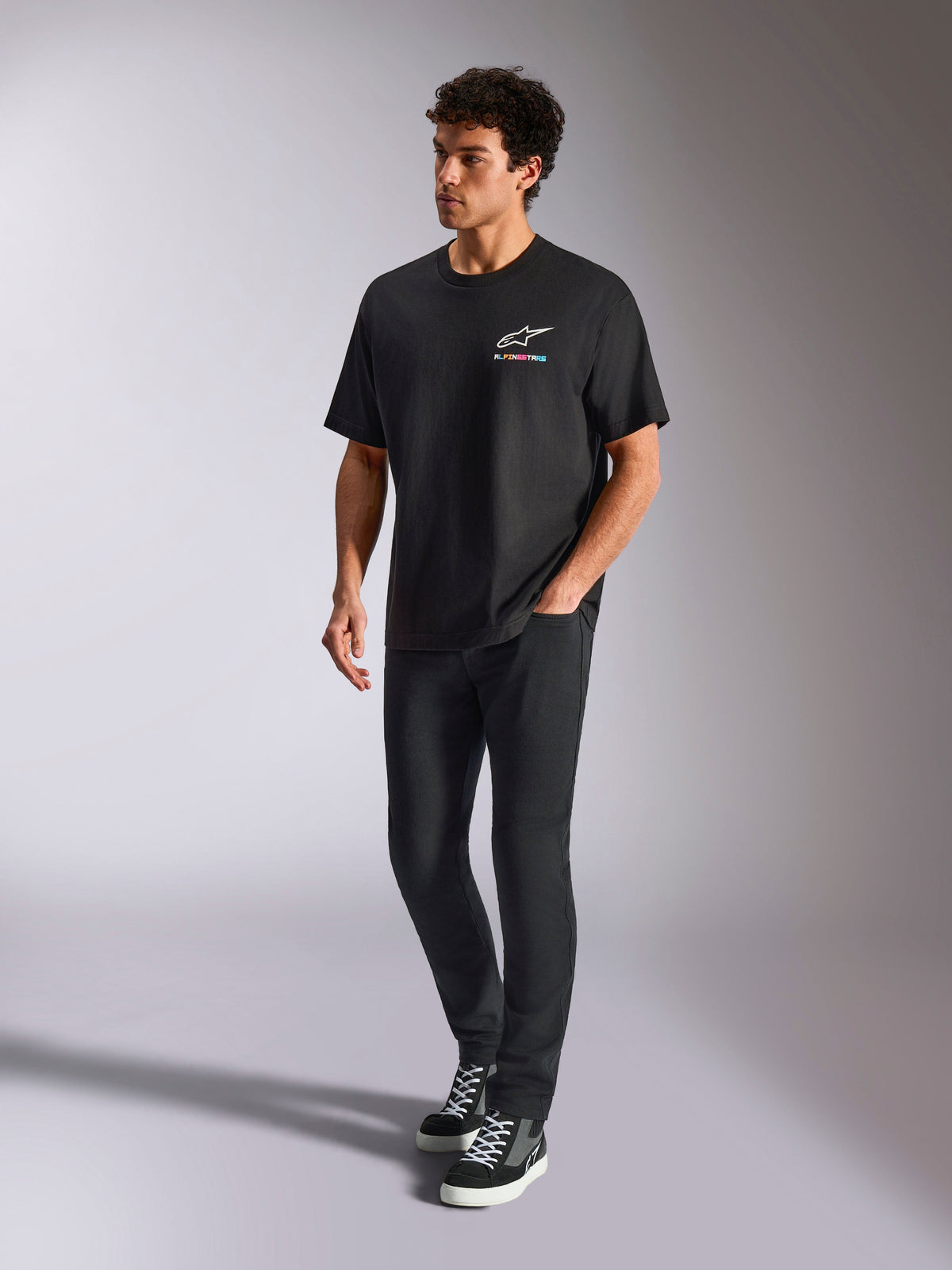 Alpinestars Wild Oversized CSF Tee, t-shirt de manga curta, preta, logótipo Astars multicolorido no peito, estilo streetwear casual, vestida por um modelo com calças pretas e sapatilhas de cano alto