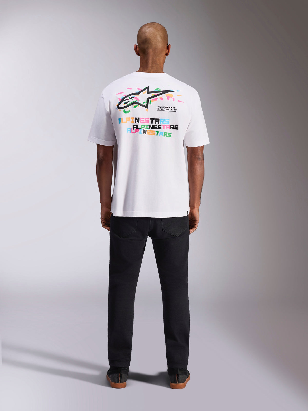 T-shirt Alpinestars Wild Oversized CSF, t-shirt de manga curta, branca, vista traseira exibindo logótipo Astars multicolor vibrante e tipografia repetida, streetwear casual inspirado no desporto motorizado