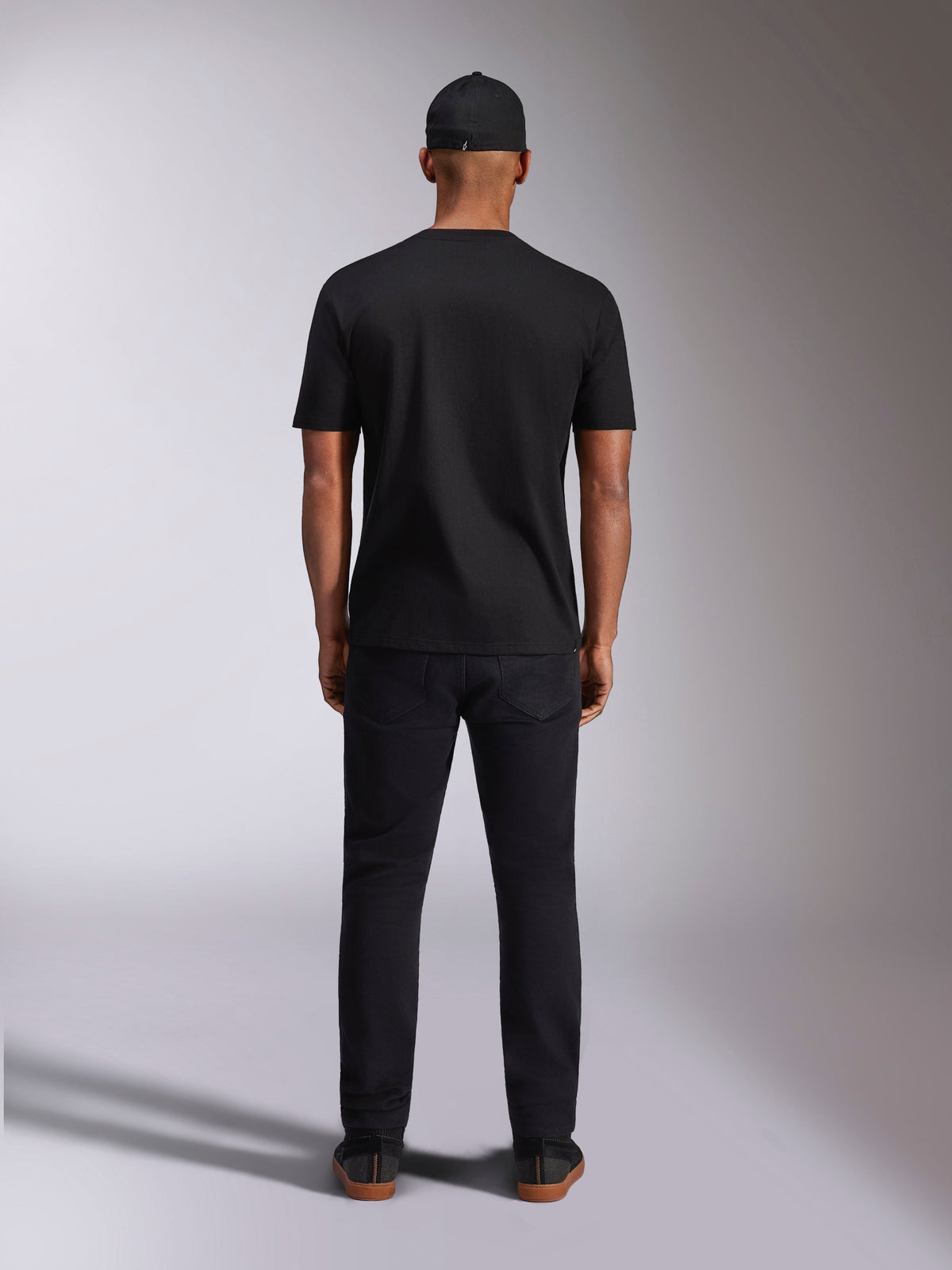Alpinestars Plate CSF Tee, t-shirt de manga curta, preta, vista de costas num modelo, usada com boné e calças pretas, streetwear casual de desportos motorizados