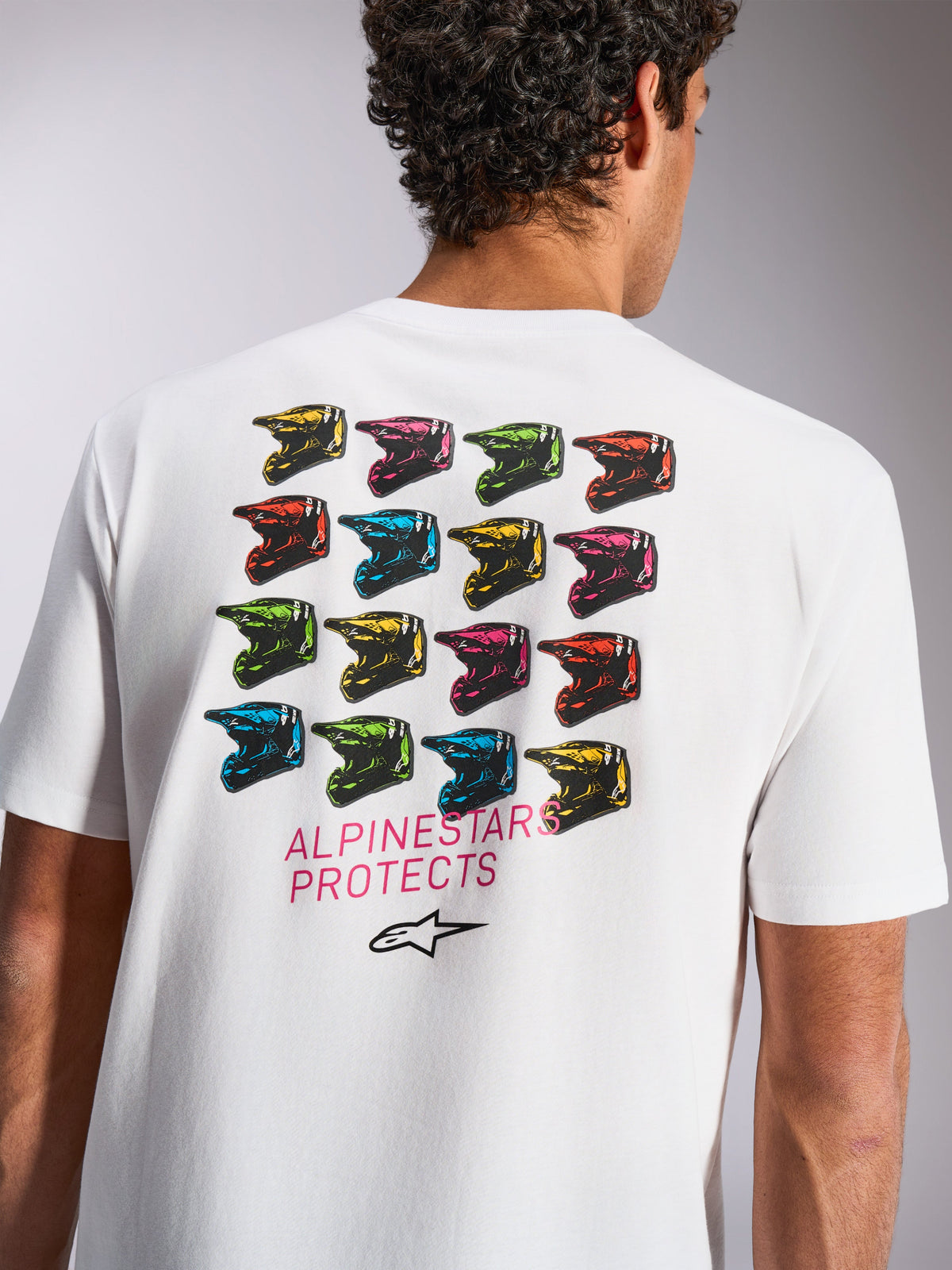 Alpinestars Pop Helmet CSF Tee, t-shirt de manga curta branca, grafismo nas costas com grelha de capacetes M10 coloridos, texto 'ALPINESTARS PROTECTS' e logótipo Astars, vestuário desportivo casual de motorsport