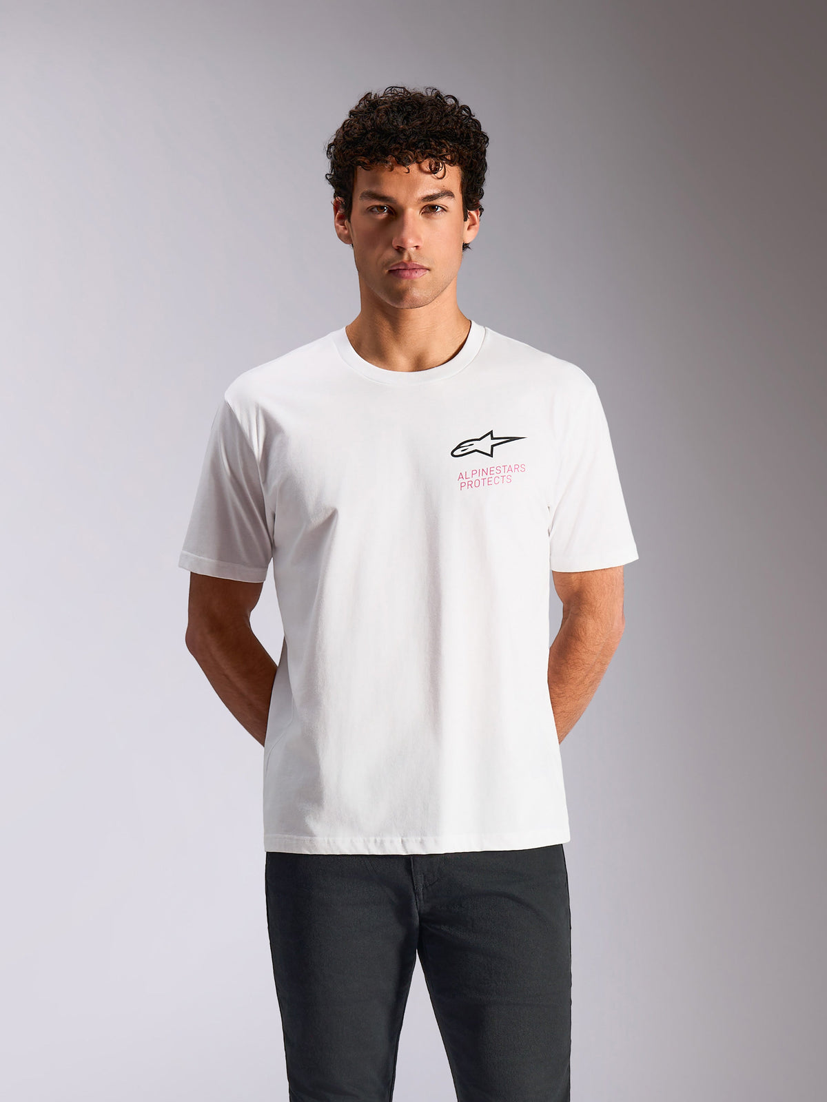 Alpinestars Pop Helmet CSF Tee, t-shirt de manga curta, branca, logótipo Astars preto com texto Alpinestars Protects em cor-de-rosa, streetwear casual inspirado no desporto motorizado