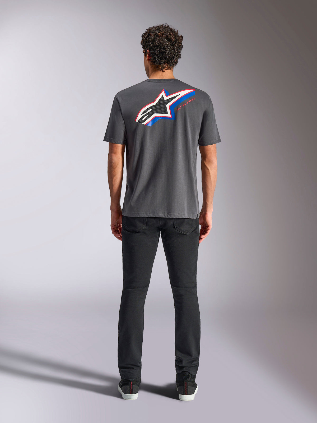 Alpinestars Angler CSF Tee, t-shirt de manga curta, cinzento escuro, logótipo Astars grande multicolorido nas costas com detalhes em vermelho e azul, vista traseira no modelo, streetwear casual de motorsport