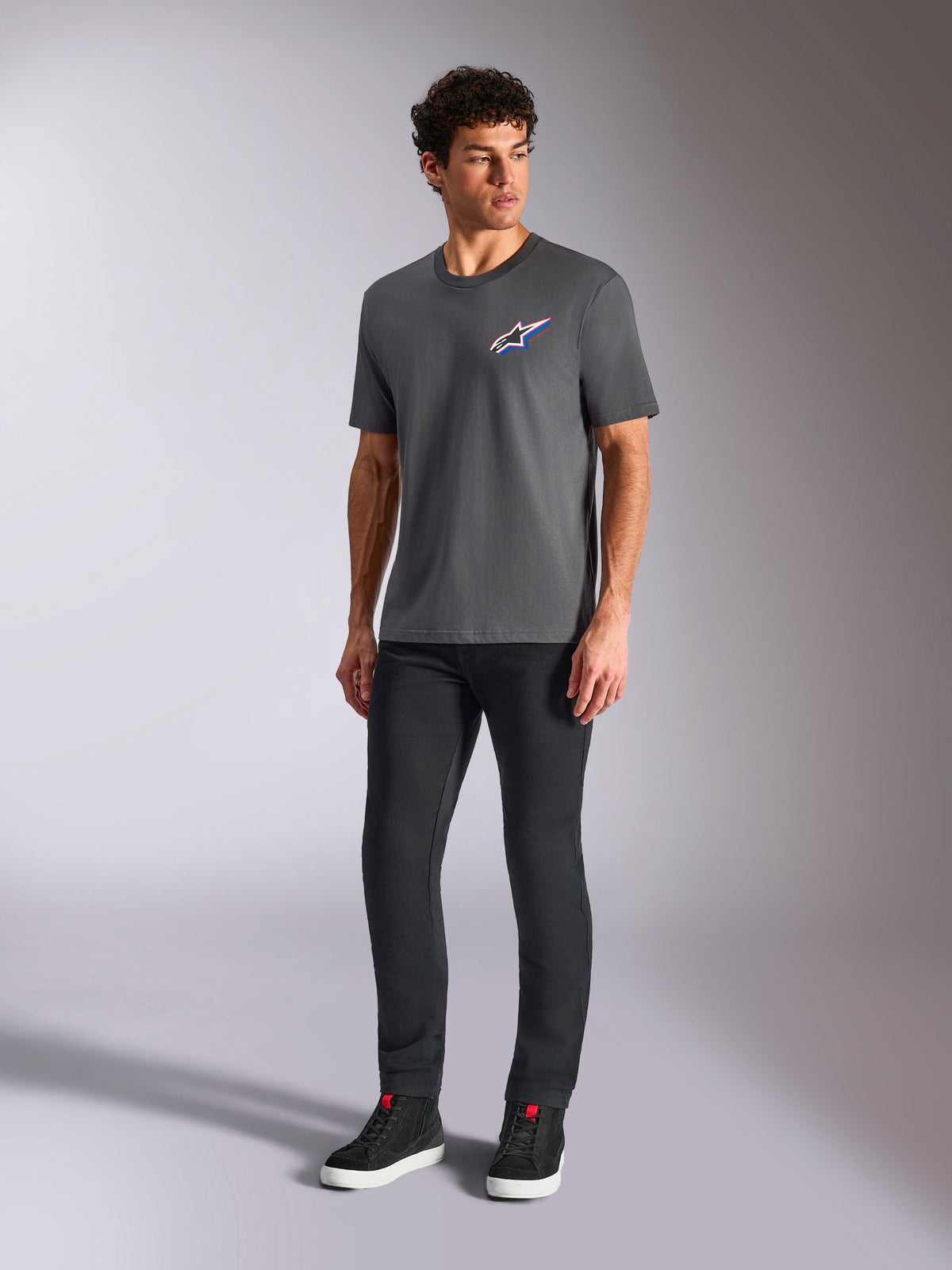 Alpinestars Angler CSF Tee, t-shirt de manga curta, antracite, logótipo Astars multicolor no peito, usada com calças pretas e sapatilhas, streetwear casual de desporto motorizado
