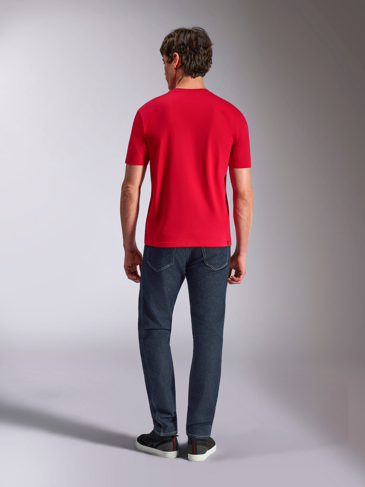 Alpinestars Authority CSF Tee, T-shirt de manga curta, vermelha, vista traseira num modelo a usar calças de ganga azul-escuro e sapatilhas pretas, streetwear casual inspirado no desporto motorizado
