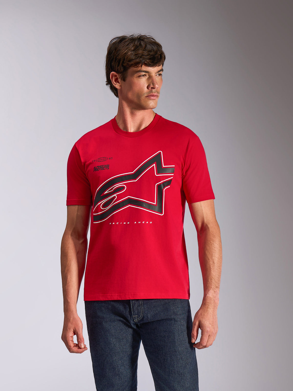 Alpinestars Authority CSF Tee, t-shirt de manga curta, vermelha, logótipo Astars grande com contorno preto e branco no peito, vestida por um modelo masculino com jeans azul-escuro, streetwear casual inspirado no desporto motorizado