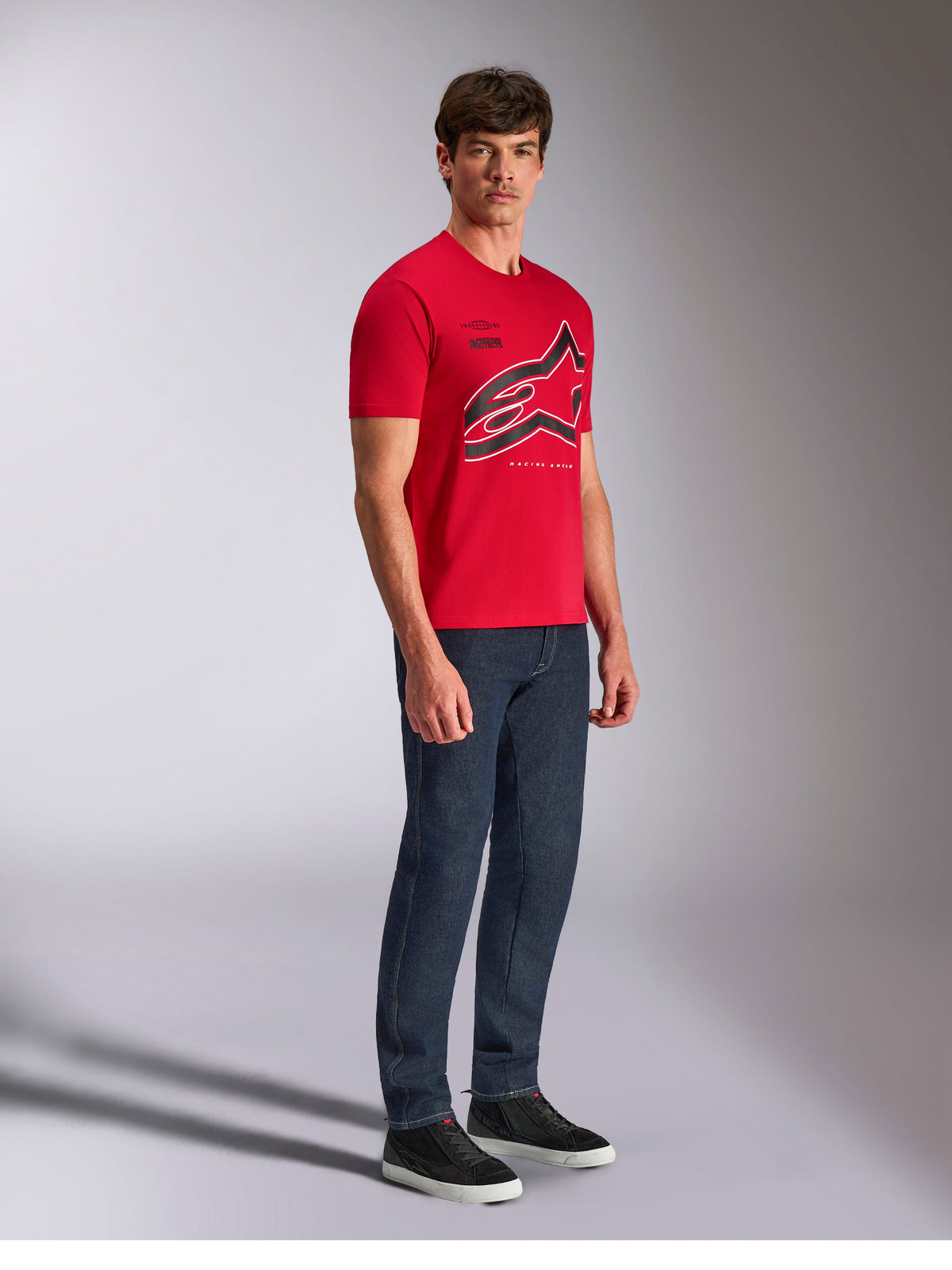 T-shirt Alpinestars Authority CSF, de manga curta, vermelha, logótipo Astars grande recortado com contornos a preto e branco, usada por modelo com calças de ganga escuras e sapatilhas pretas, streetwear casual inspirado no desporto motorizado