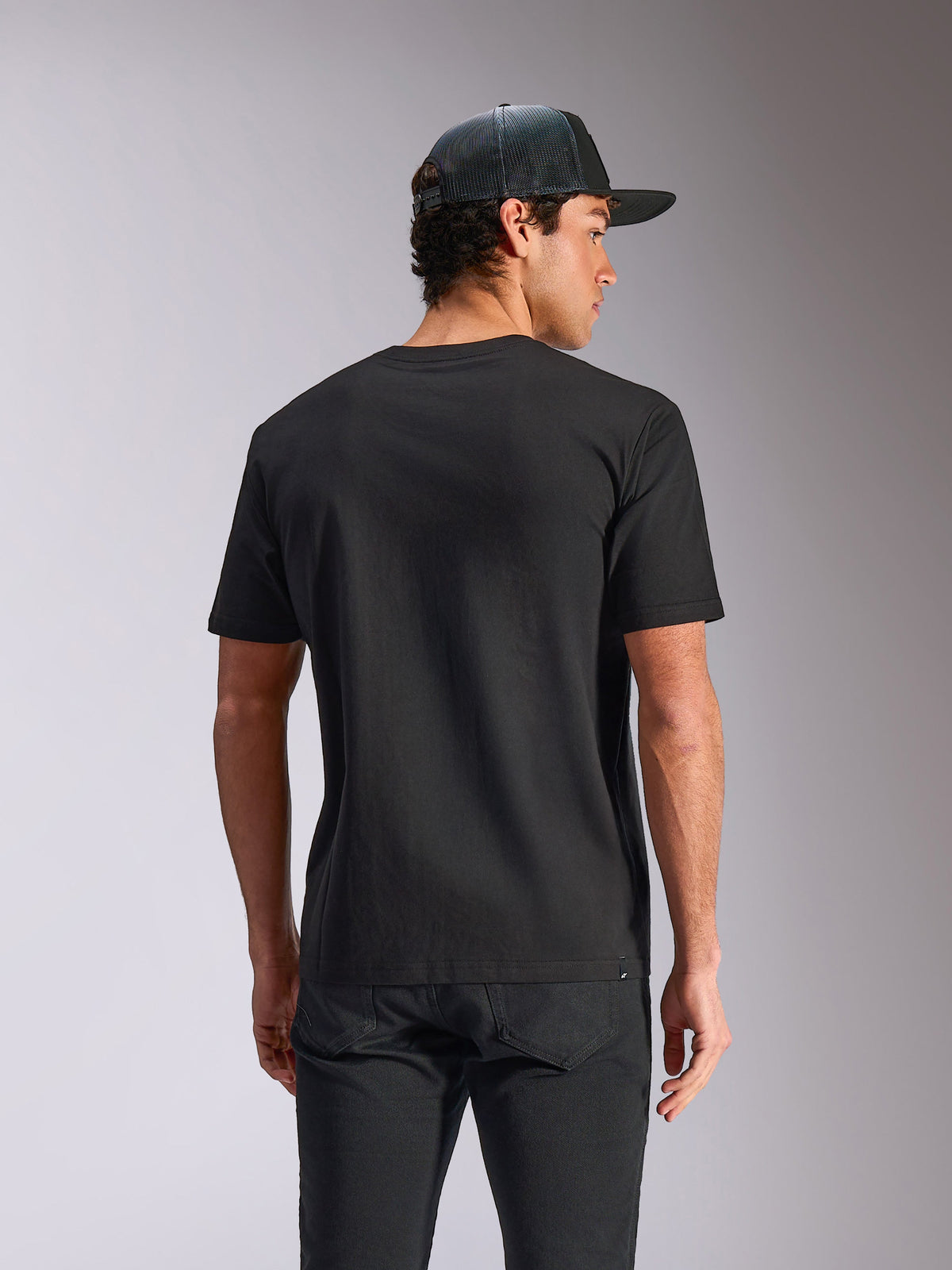 Alpinestars Verdure Camo CSF Tee, T-shirt de manga curta, preta, vista traseira, usada com um boné de rede e calças pretas, streetwear casual de desportos motorizados