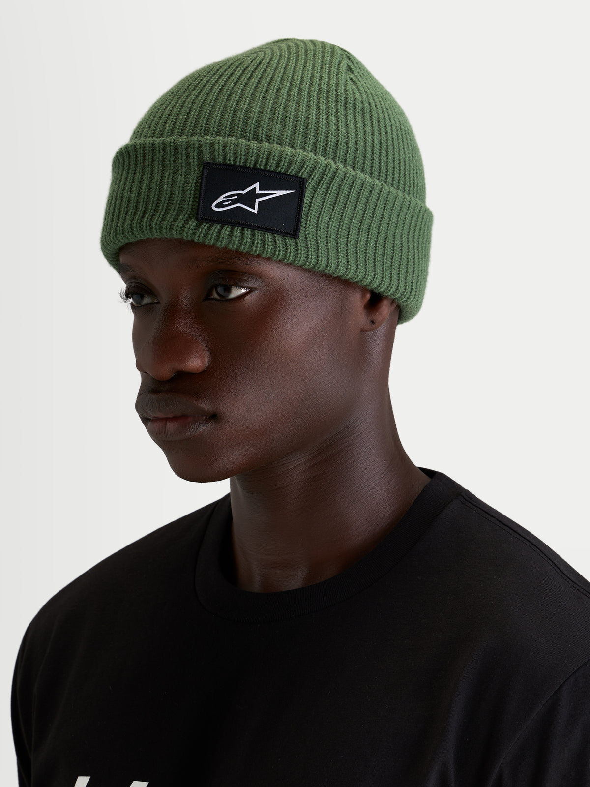 Alpinestars Gorro Unload Rib Cuff, gorro casual em verde ervilha, num modelo a usar malha jersey e patch tecido frontal SAstars preto e branco