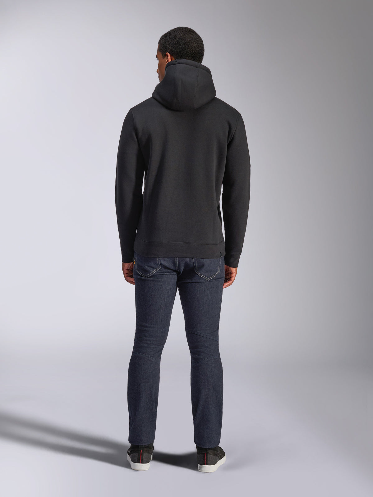 Alpinestars Blaze V3 Hoodie, streetwear casual, preto, vista traseira de camisola com capuz, usada com calças de ganga azul escuras e sapatos pretos, design simples inspirado no desporto motorizado