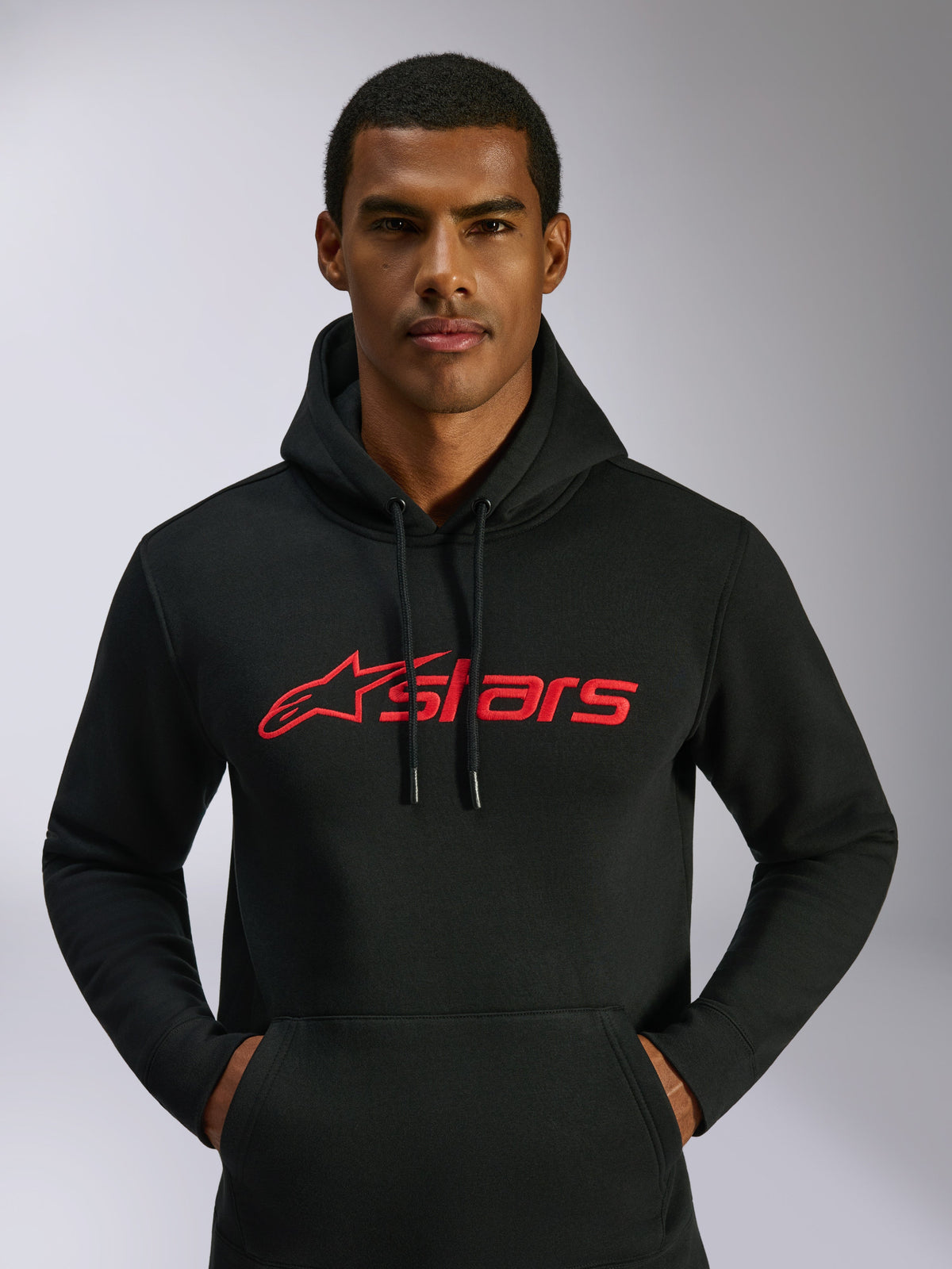 Alpinestars Blaze V3 Hoodie, streetwear casual, preto com logótipo Alpinestars vermelho no peito, usado por um homem, capuz com cordão, mangas compridas, design moderno inspirado no desporto motorizado