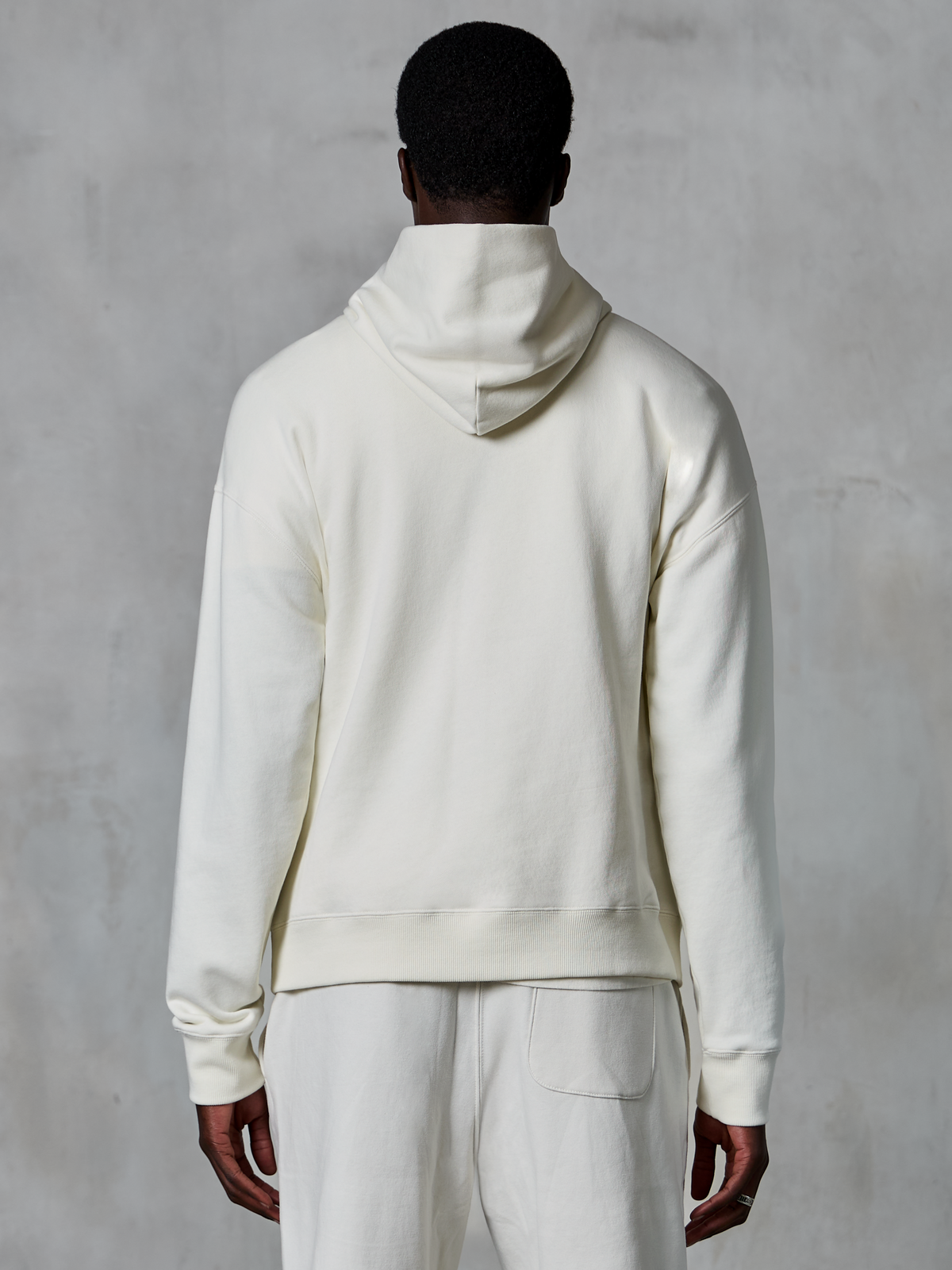Hoodie Alpinestars Essentials Ageless, hoodie pullover off-white, vista de costas no modelo, design limpo e minimalista, calças casuais a condizer, corte relaxado para conforto diário