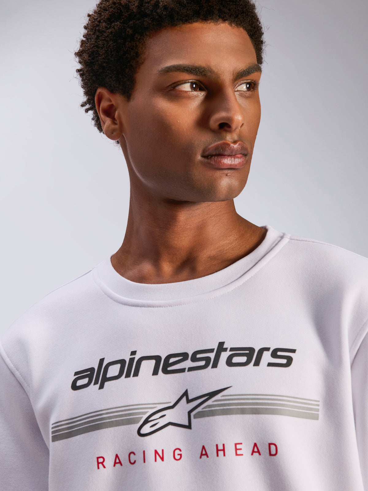 Alpinestars Bettern Crew, sweatshirt de gola redonda branca em lã polar, logótipo Alpinestars preto com linhas horizontais cinzentas e texto 'Racing Ahead' em vermelho, streetwear casual inspirado no desporto motorizado