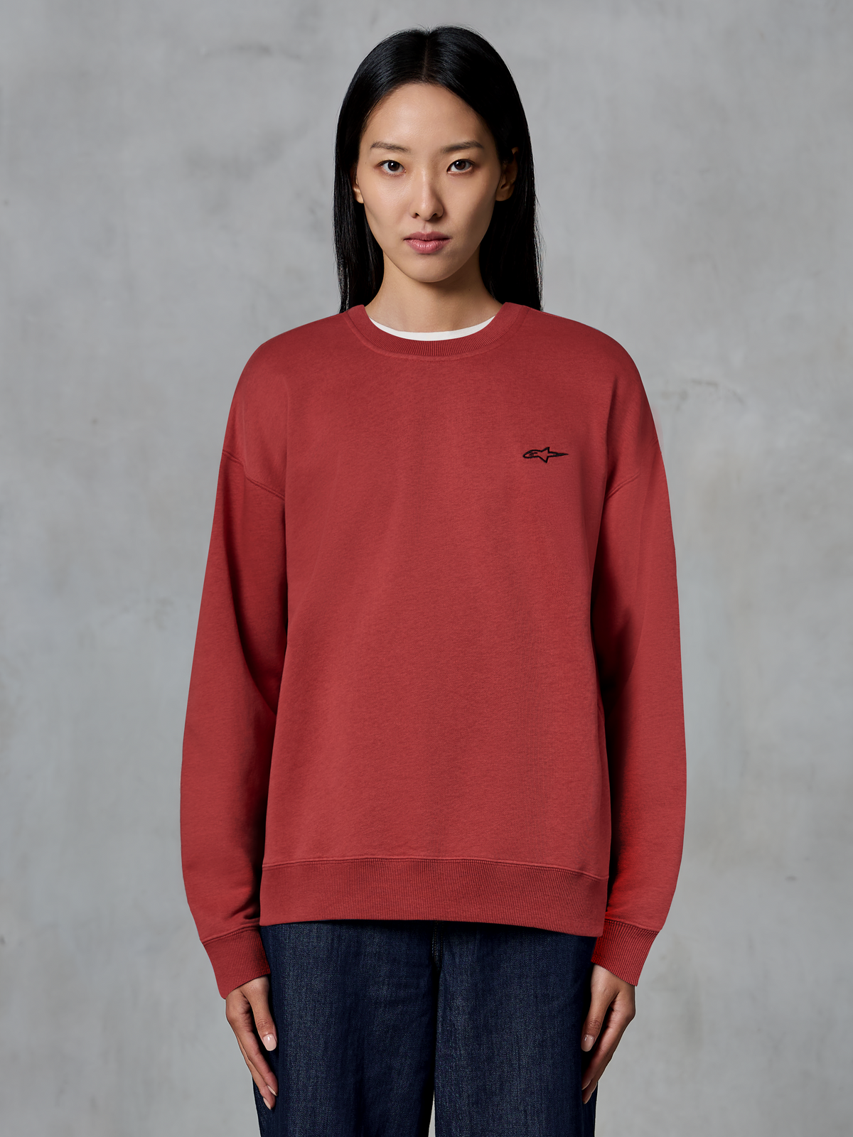Alpinestars Essentials Ageless Crew, Brick Red crewneck sweatshirt, small black logo on chest, premium fleece, worn by model, casual motorsport-inspired streetwear