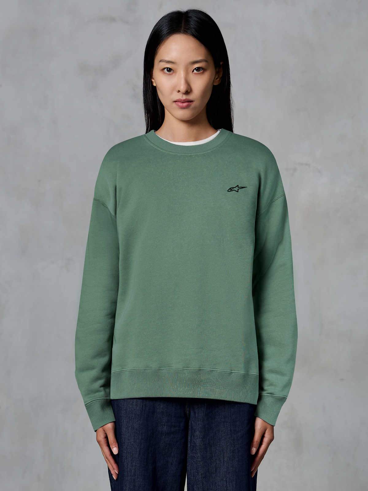 Alpinestars Essentials Ageless Crew, sweatshirt de gola redonda, Verde Cactus, usada por uma modelo, pequeno logótipo preto no peito, gola, punhos e bainha canelados, streetwear casual de desporto motorizado