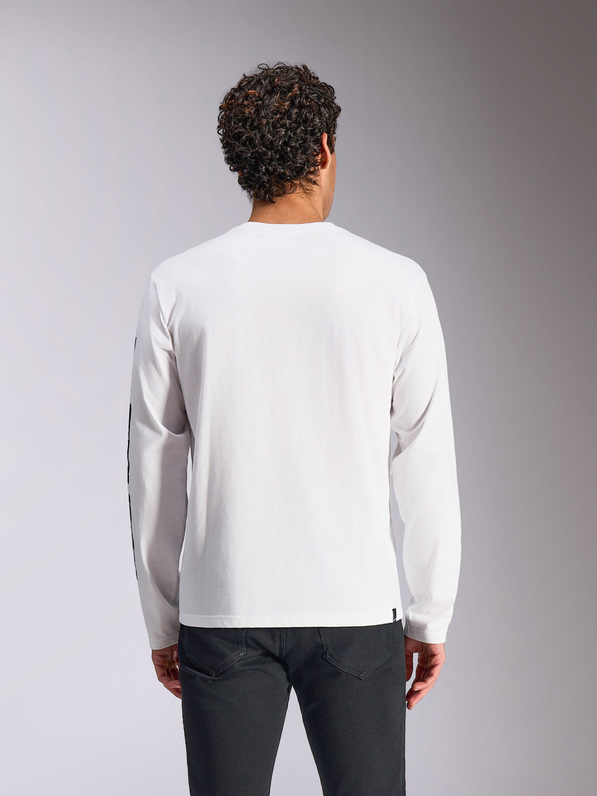 Alpinestars Trackside CSF Tee - Manga Comprida, branco, vista de costas num modelo, combinado com calças pretas, tecido branco com mangas compridas, streetwear casual inspirado no desporto motorizado