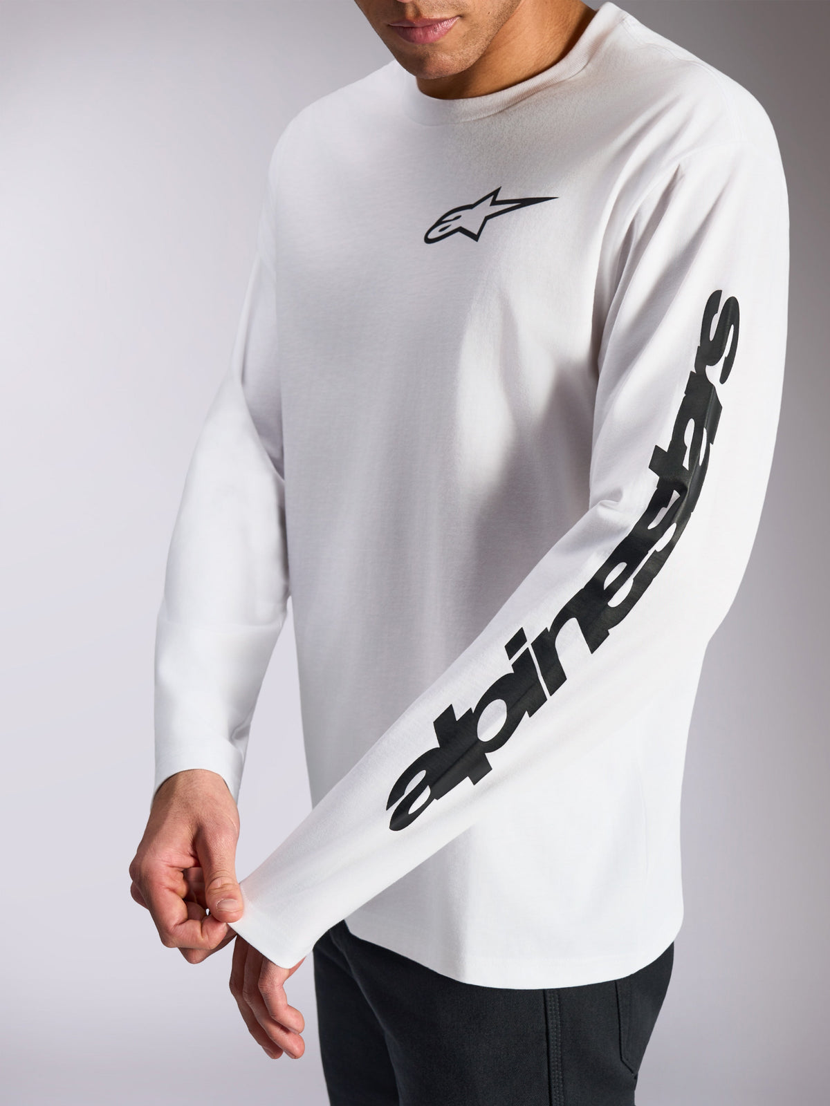 Alpinestars Trackside CSF Tee, T-shirt de manga comprida, branca e preta, pequeno logótipo de estrela preto no peito e marca nominativa em destaque na manga, streetwear casual inspirado no desporto motorizado