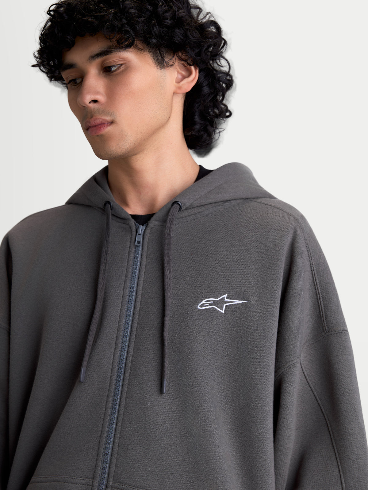 Alpinestars Entity Oversized Hoodie, Sportswear Zip Fleece for Men and Women, Charcoal Gray, 80% Cotton and 20% Recycled Polyester, featuring a Vislon front zipper, self-lined hood with flat drawcords, and a white Astars logo embroidered on the chest.