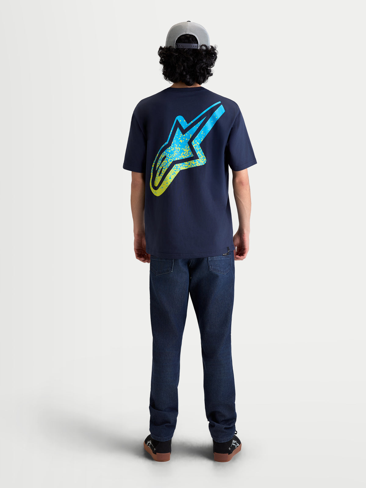 Alpinestars T-Shirt Meteor CSF, t-shirt de manga curta azul marinho, vista traseira no modelo com logótipo Astars grande inspirado no MX em gradação amarelo e ciano, sportswear casual em mistura de algodão e poliéster