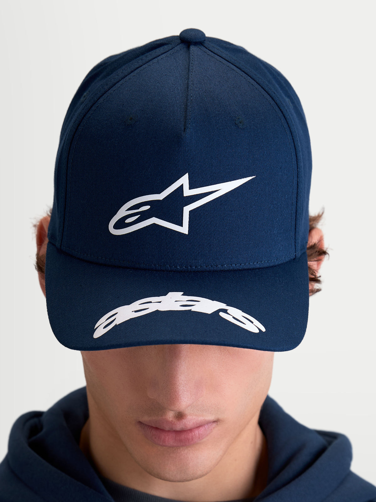 Alpinestars Chapéu Arclight, boné de basebol sportswear unissexo, azul marinho e branco, com copa estruturada, logótipo Astars em relevo texturizado e aba curva com marca Astars, construção em sarja de algodão, vista frontal no modelo.