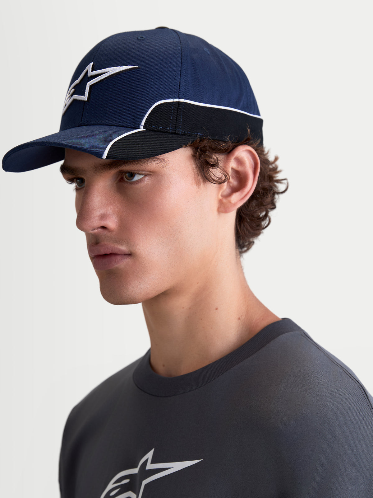 Alpinestars boné 500 Snapback, boné de sportswear unissexo, azul-marinho e preto, em sarja de algodão, aba curva, logótipo Astars bordado em 3D com debrum branco contrastante, vista lateral no modelo.