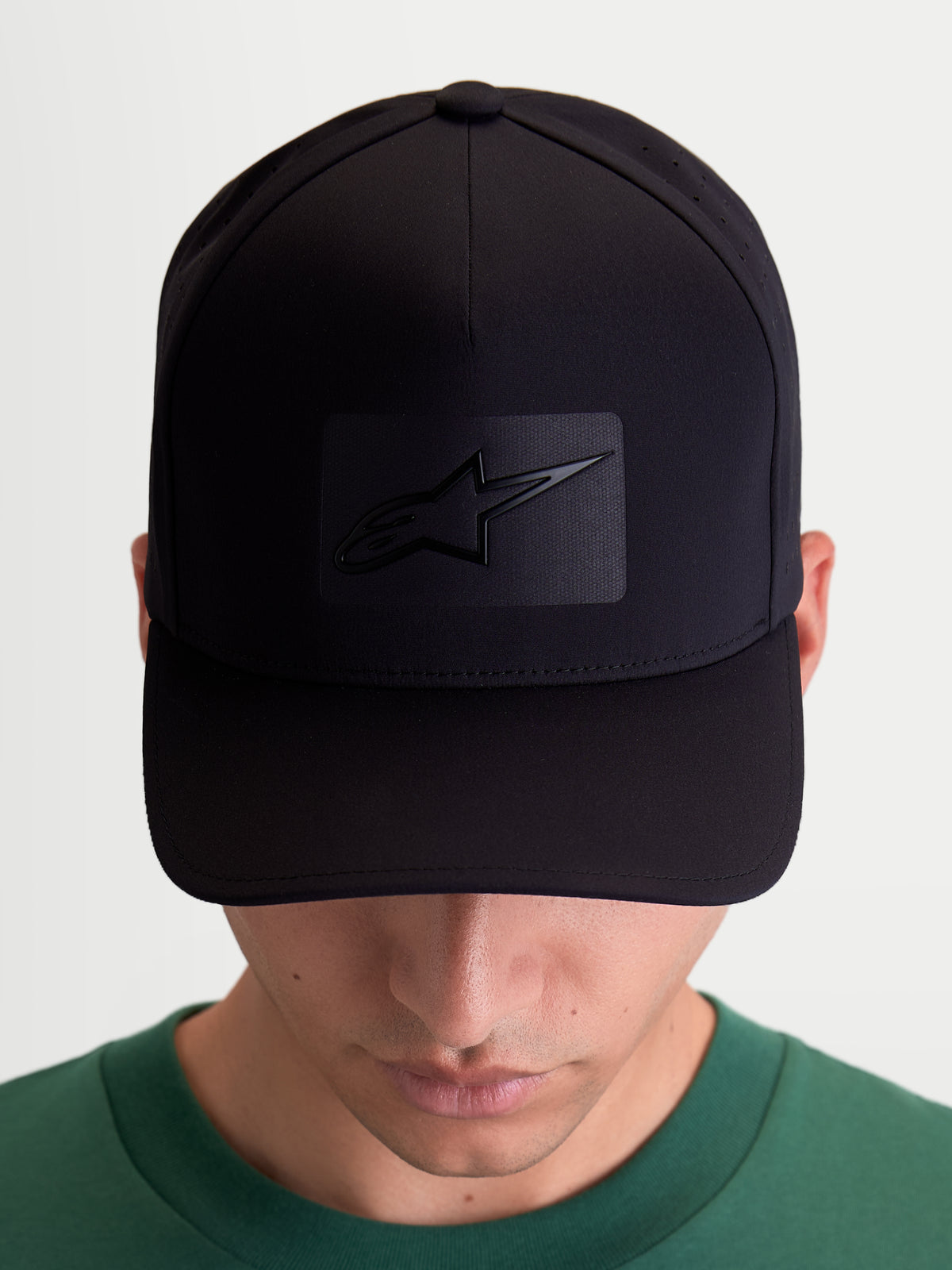 Boné Alpinestars Algo Perf Adjustable, boné de sportswear unissexo, preto, tecido técnico com perfurações laterais, aba curva e coroa estruturada, vista frontal em modelo com logótipo Astars em soldadura sónica.