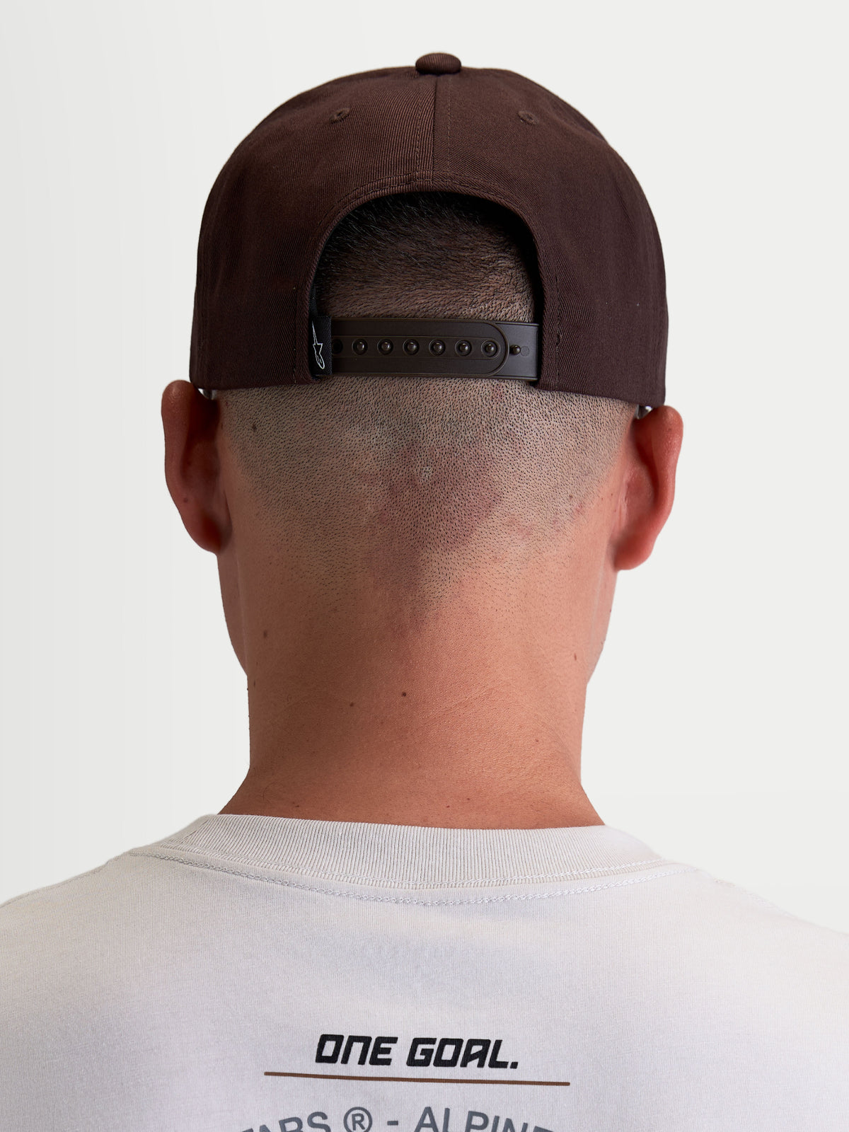 Alpinestars Boné Combo Logo Snapback, boné de casual sportswear inspirado no motorsport, unissexo, castanho, em sarja durável. Vista traseira num modelo que mostra o fecho snapback ajustável e a etiqueta da marca.