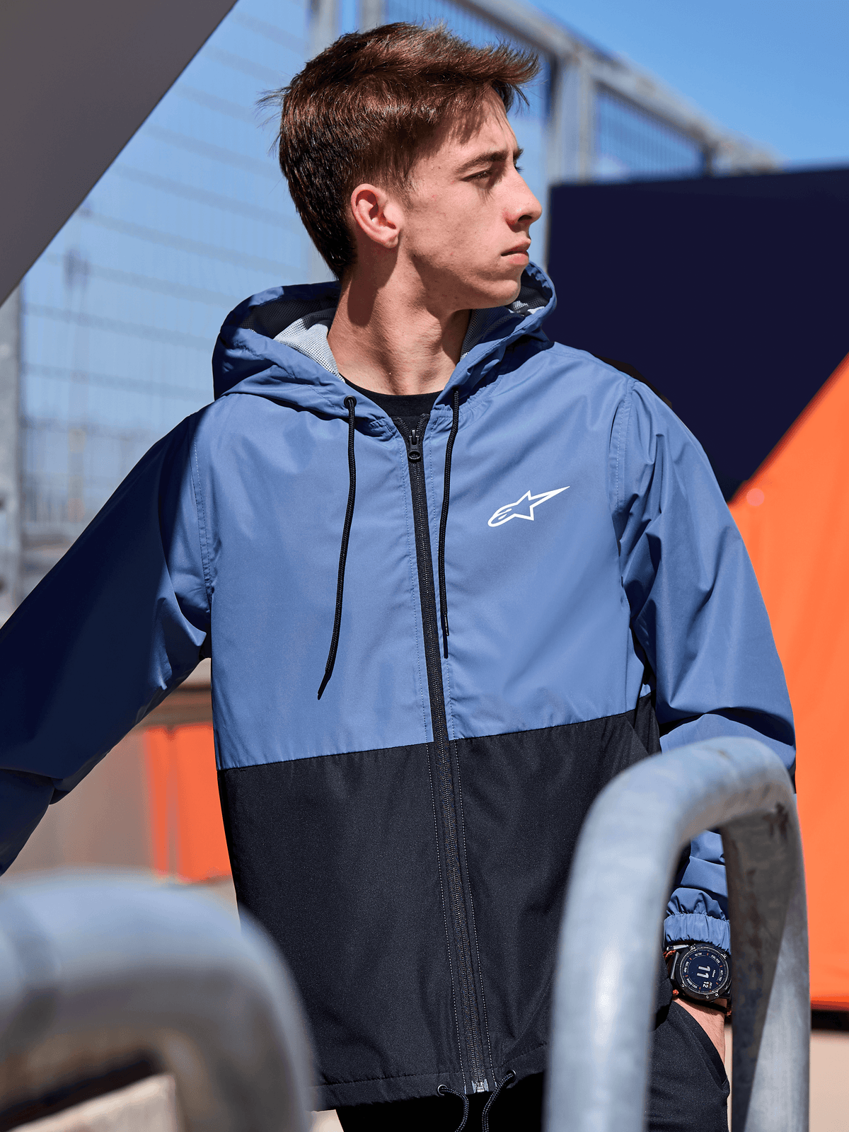 Casaco Corta-Vento Alpinestars Speeder, casaco corta-vento leve com capuz, design de blocos de cor em azul e preto, logótipo Alpinestars branco no peito, forro em malha e capuz com cordões, streetwear casual inspirado no desporto motorizado