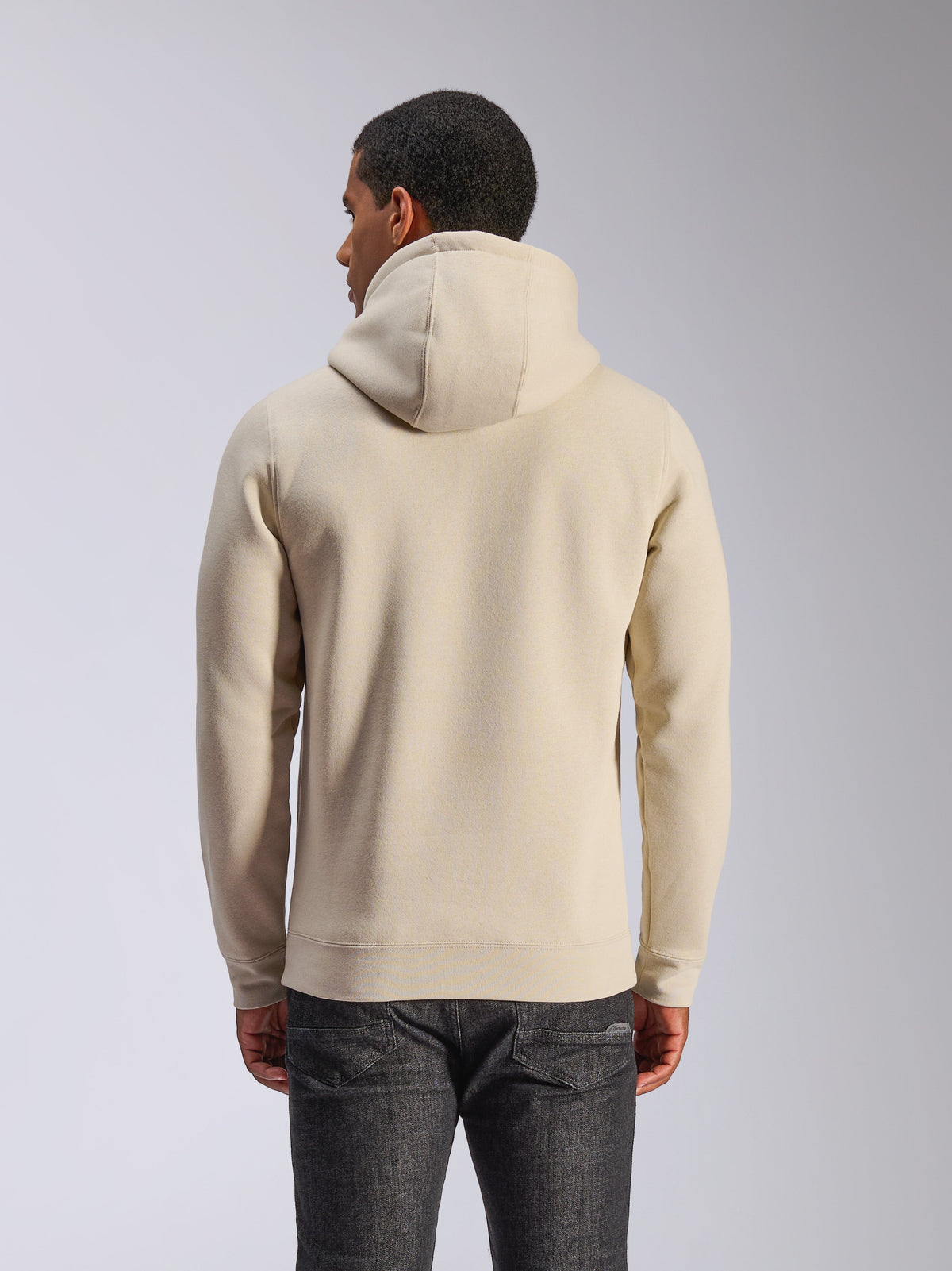Alpinestars Ageless V3 Hoodie, off-white, back view, casual sportswear, featuring a jersey-lined hood, long sleeves with ribbed cuffs and hem, worn with dark denim jeans