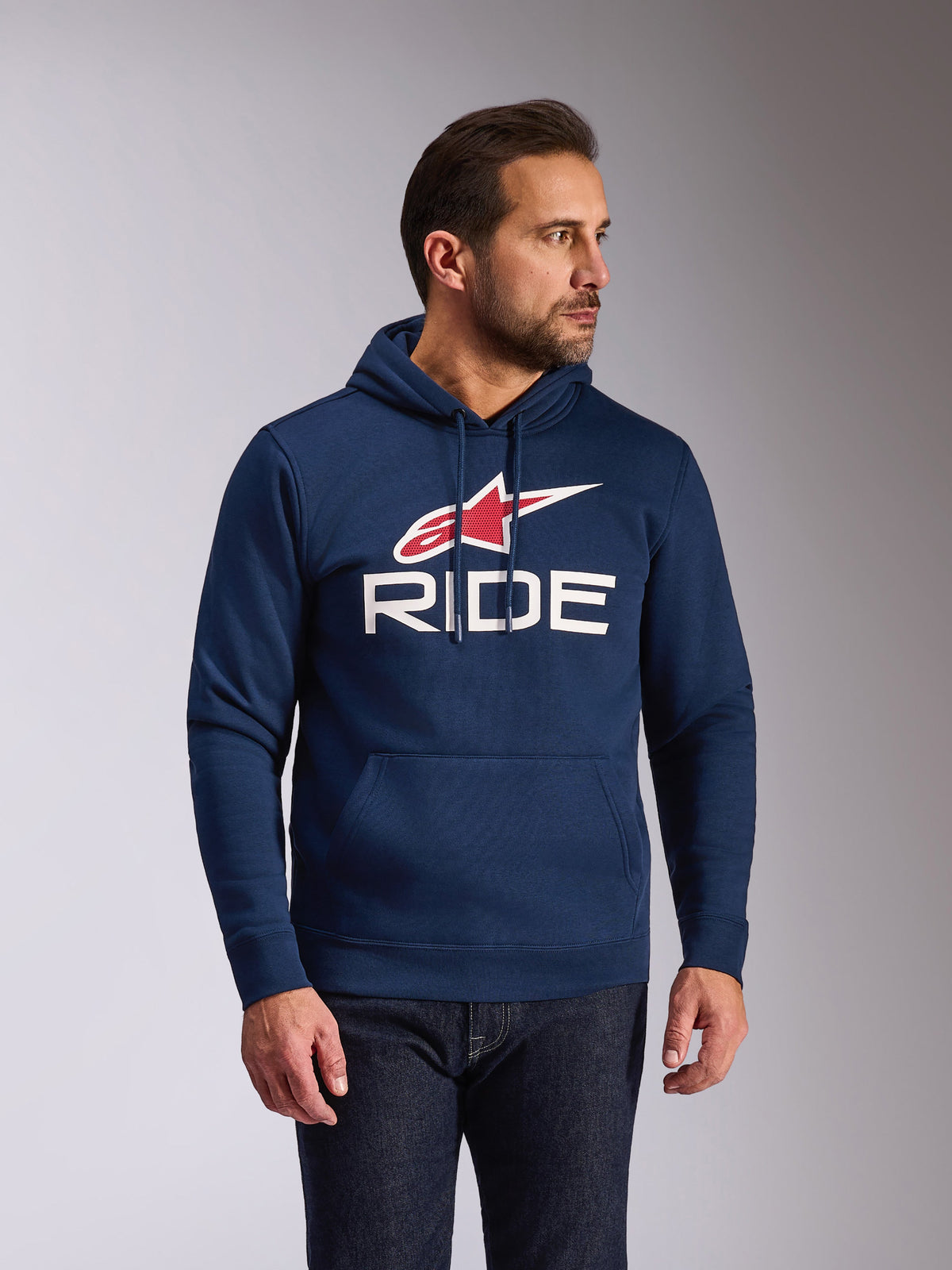 Alpinestars Ride V3 Hoodie, camisola casual em tecido polar azul marinho, com logótipo RIDE branco e símbolo de estrela Alpinestars vermelho, capuz com forro em jersey e cordões, bolso frontal tipo canguru, streetwear moderno inspirado no desporto motorizado